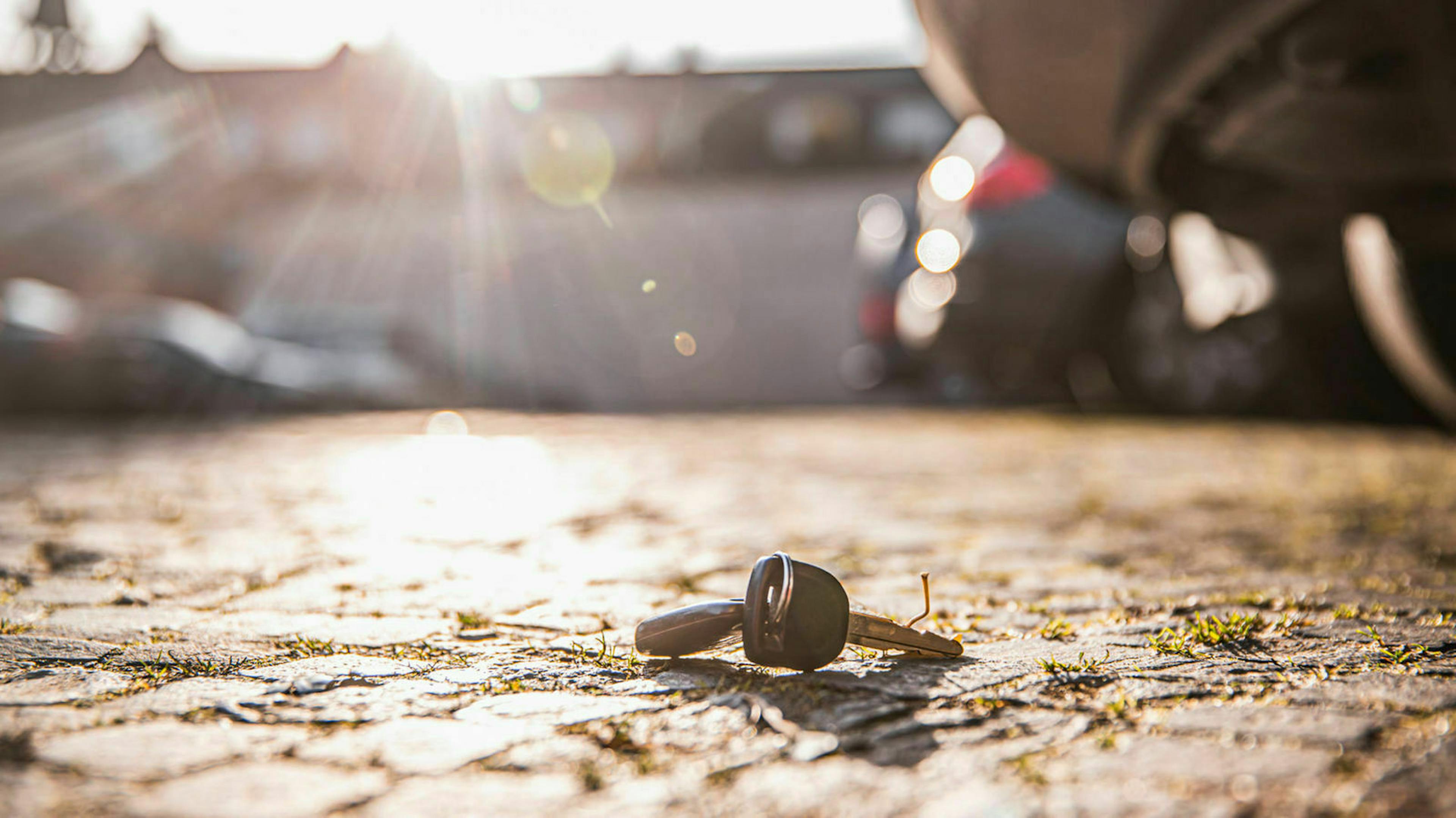 Ein Autoschlüssel liegt auf Altstadt-Kopfsteinpflaster