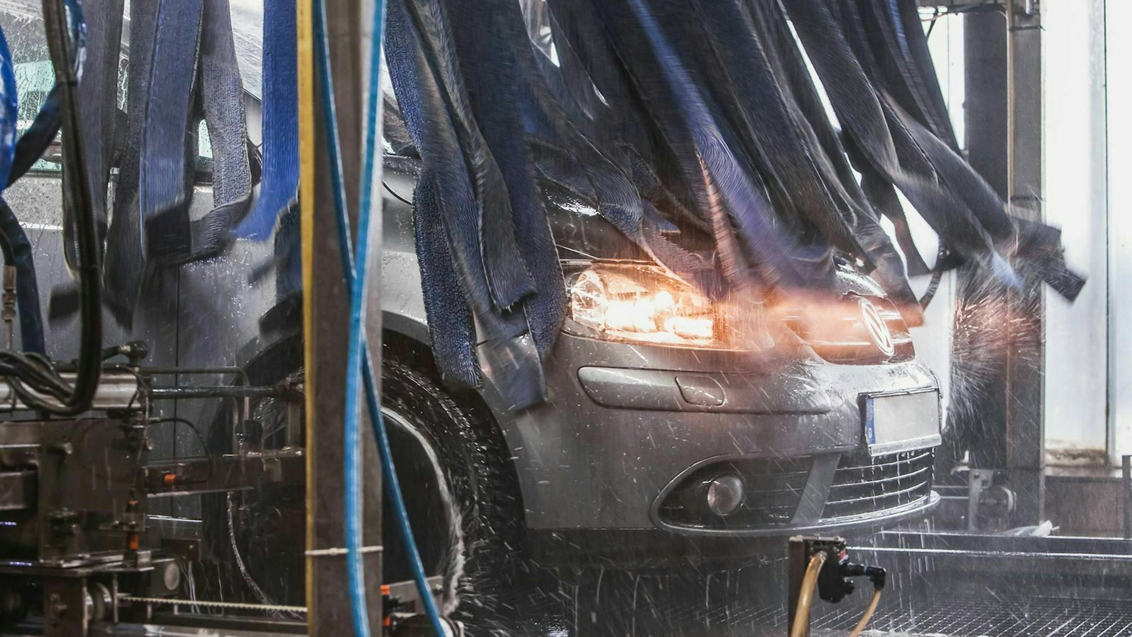 Ein dunkelgrauer VW Golf Plus steht in einer Autowaschanlage. 