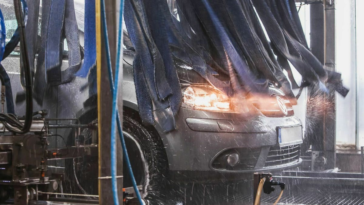 Ein dunkelgrauer VW Golf Plus steht in einer Autowaschanlage.