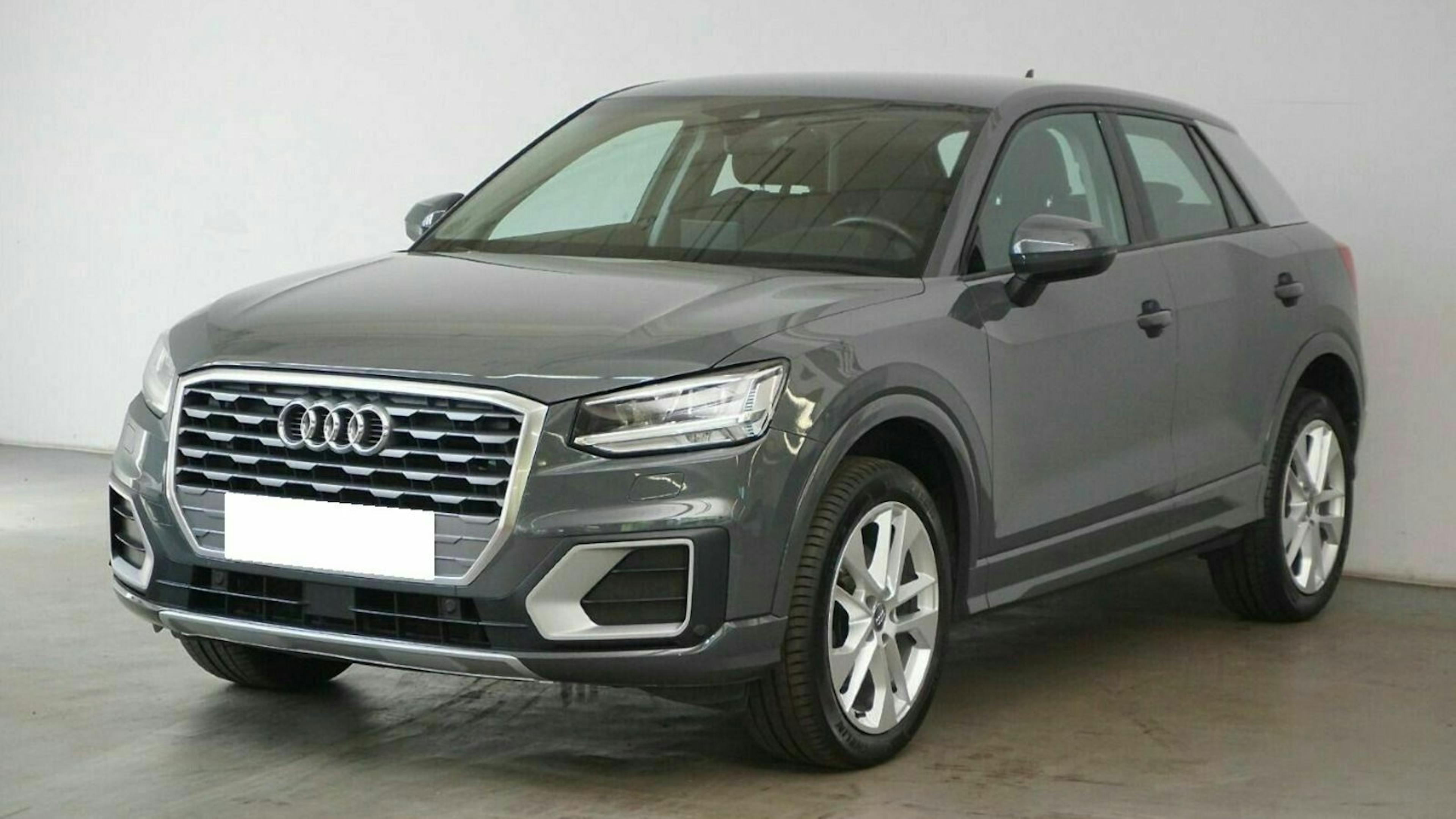 Grauer Audi Q2 SUV in einem Showroom. Frontansicht mit markantem Kühlergrill und glänzenden Felgen.