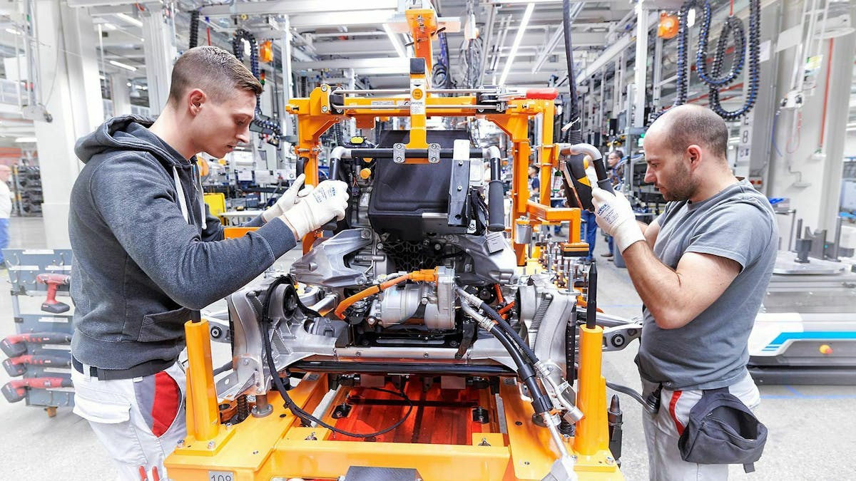 Zwei Arbeiter montieren eine Antriebseinheit eines Audi E-Tron