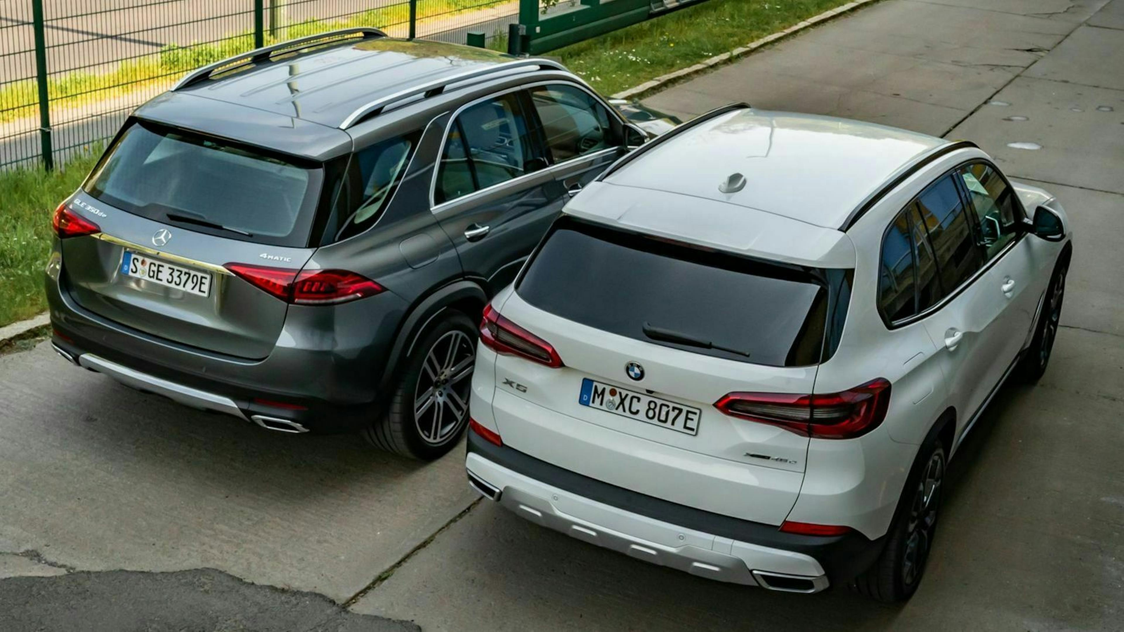 Zu sehen sind der Mercedes GLE und der BMW X5 von hinten