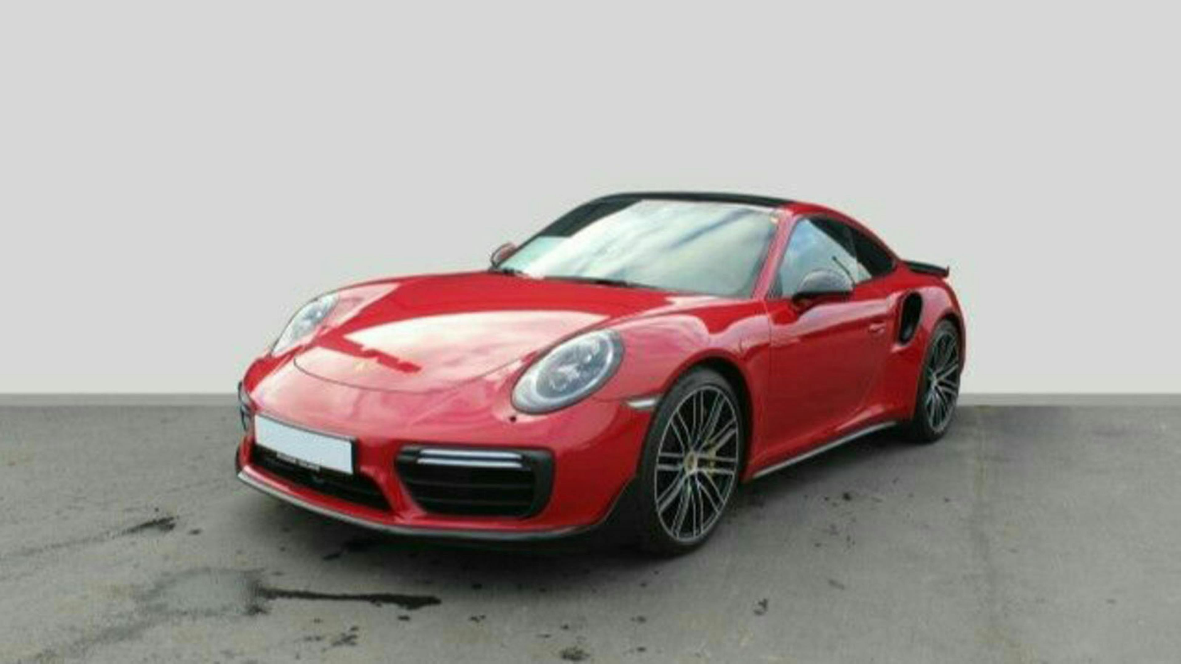Ein roter Porsche 911 mit Heckantrieb steht vor einer weißen Wand