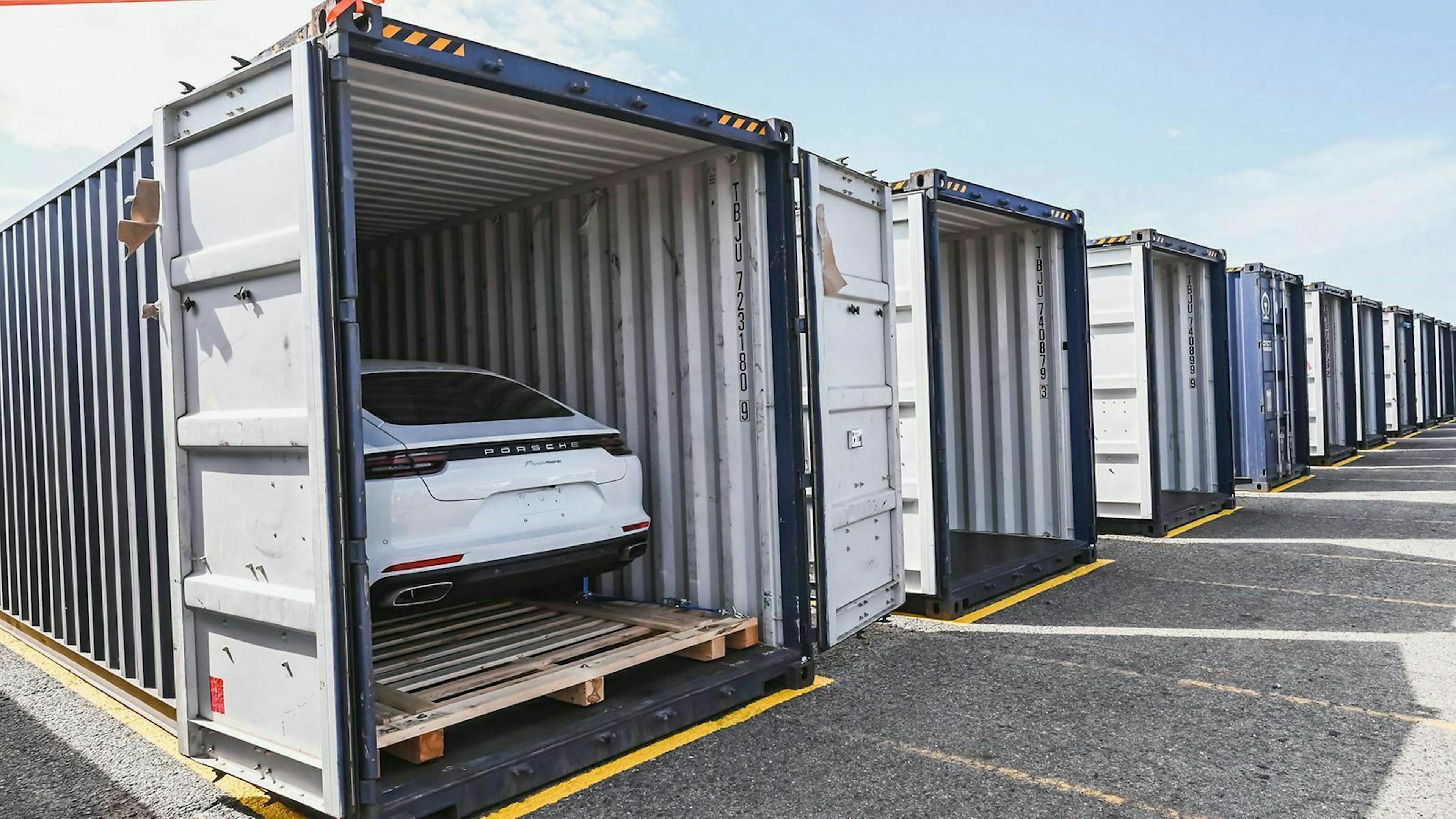 Offen stehende Container auf Asphalt. In einem Container steht ein Fahrzeug.