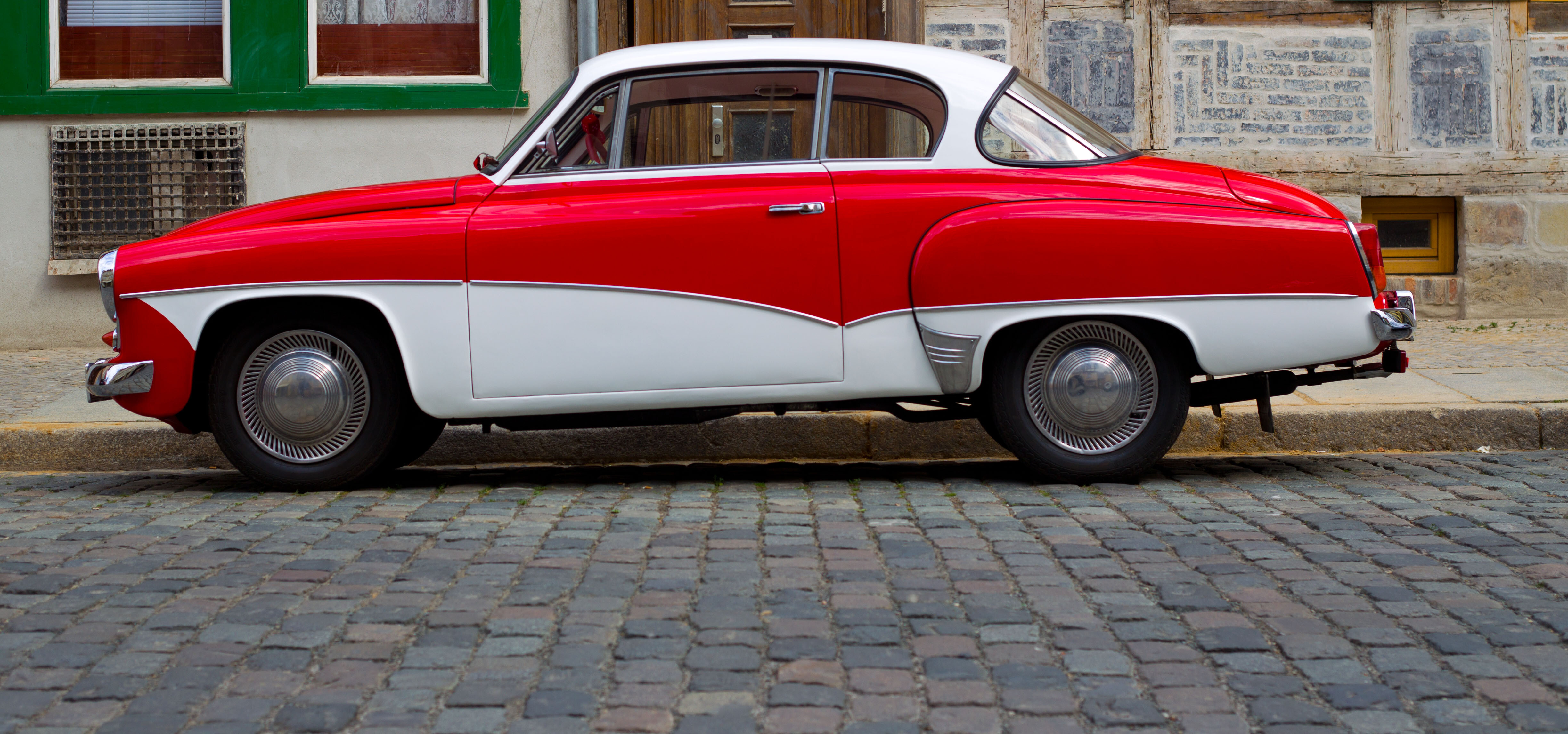 Rot-weißer Wartburg 311 in Seitenansicht auf Kopfsteinpflaster, geparkter Oldtimer