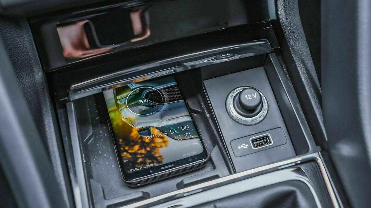 Qi Laden im Auto: Ein Smartphone liegt in der Mittelkonsole eines Autos und lädt seinen Akku kabellos.