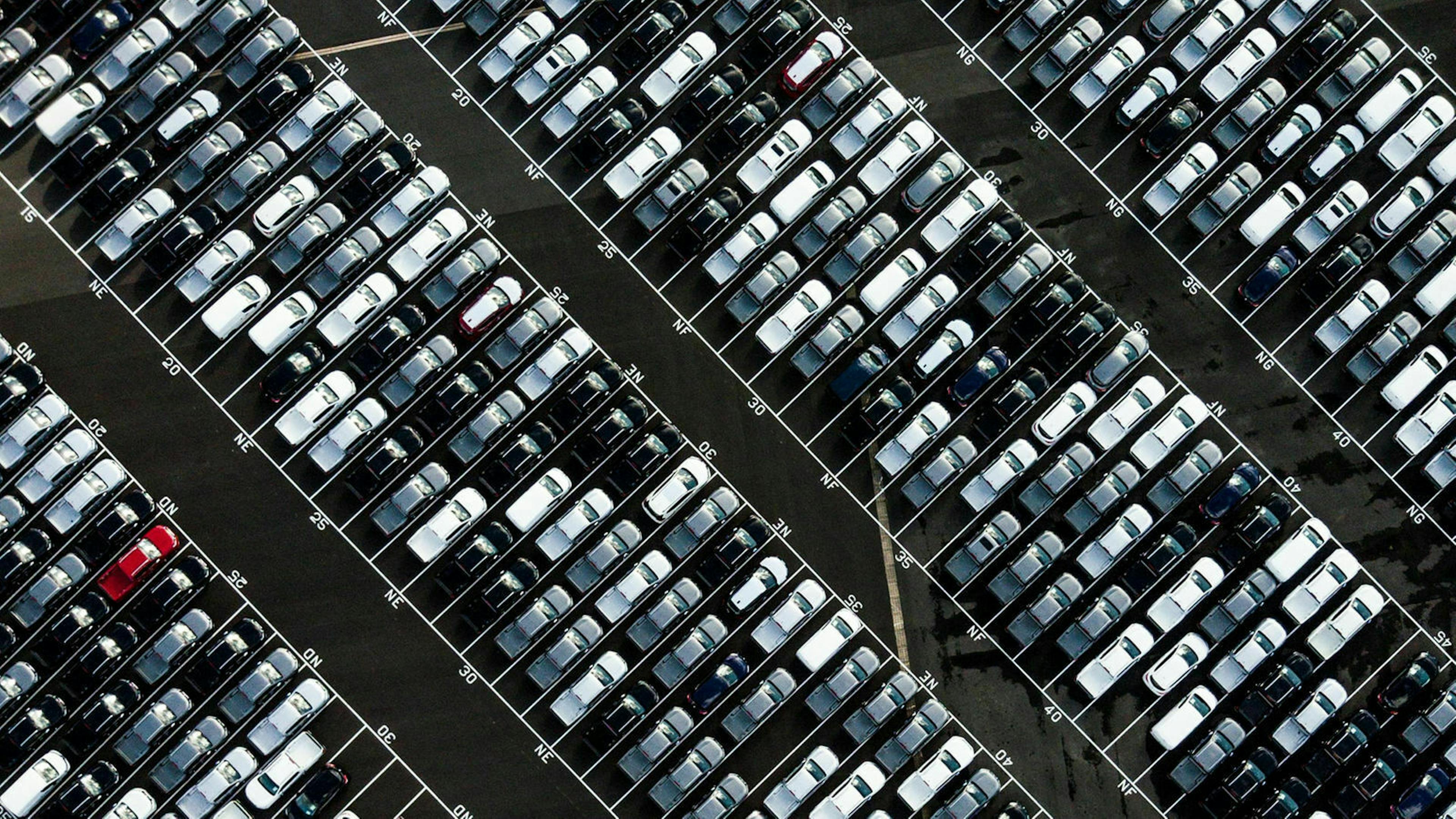 Luftaufnahme eines Parkplatzes, auf dem zahlreiche Neuwagen stehen