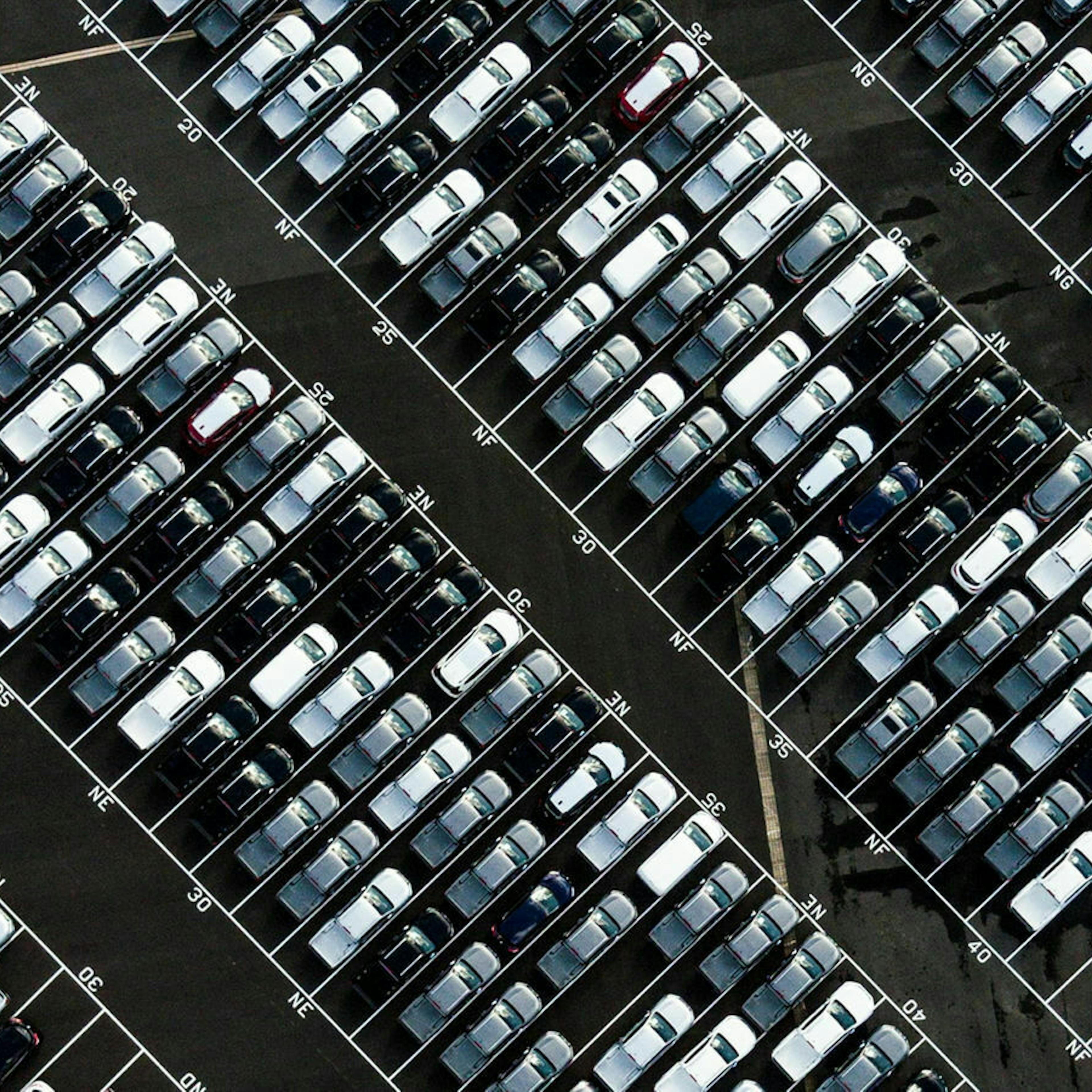 Luftaufnahme eines Parkplatzes, auf dem zahlreiche Neuwagen stehen