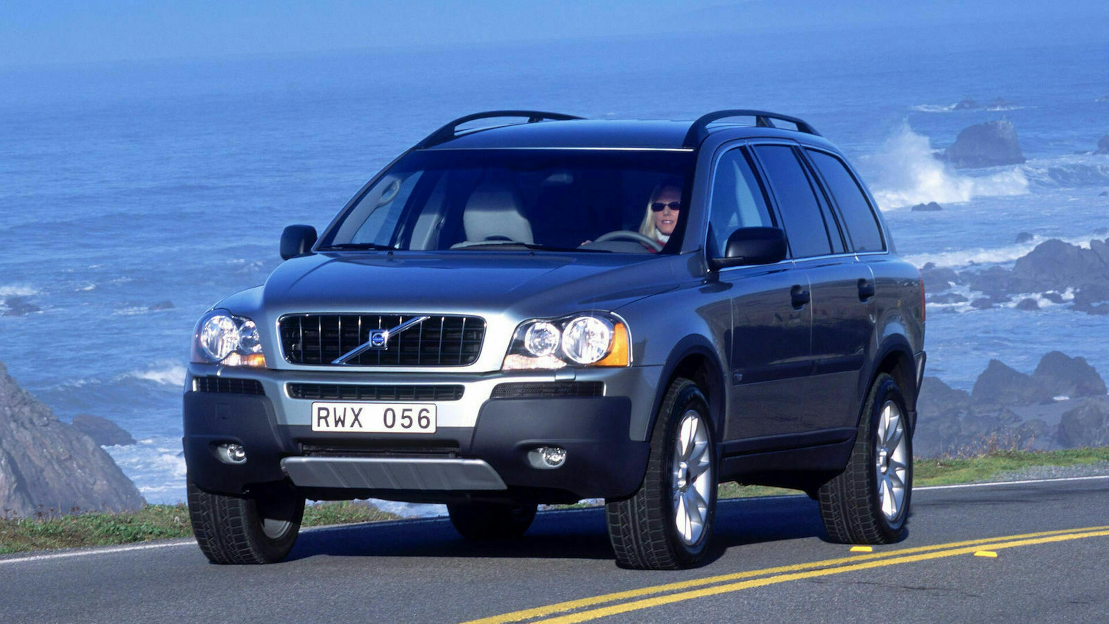 Ein schwarzer Volvo XC90 fährt eine Küstenstraße entlang am Meer vorbei