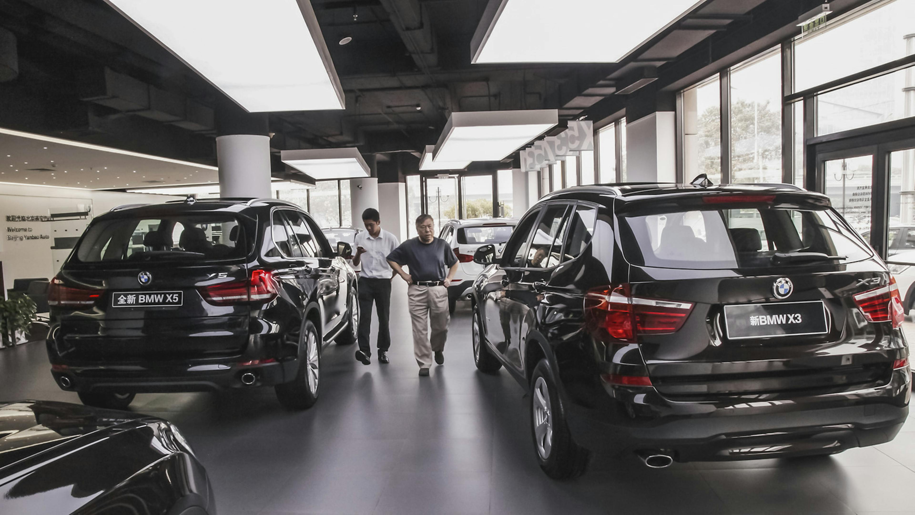 Zwei Personen gehen durch eine Reihe von geparkten SUV hindurch.