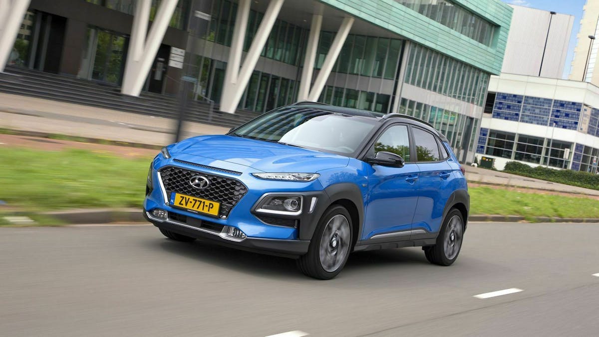 Blauer Hyundai Kona in einer Stadt fahrend, Ansicht von links-vorne