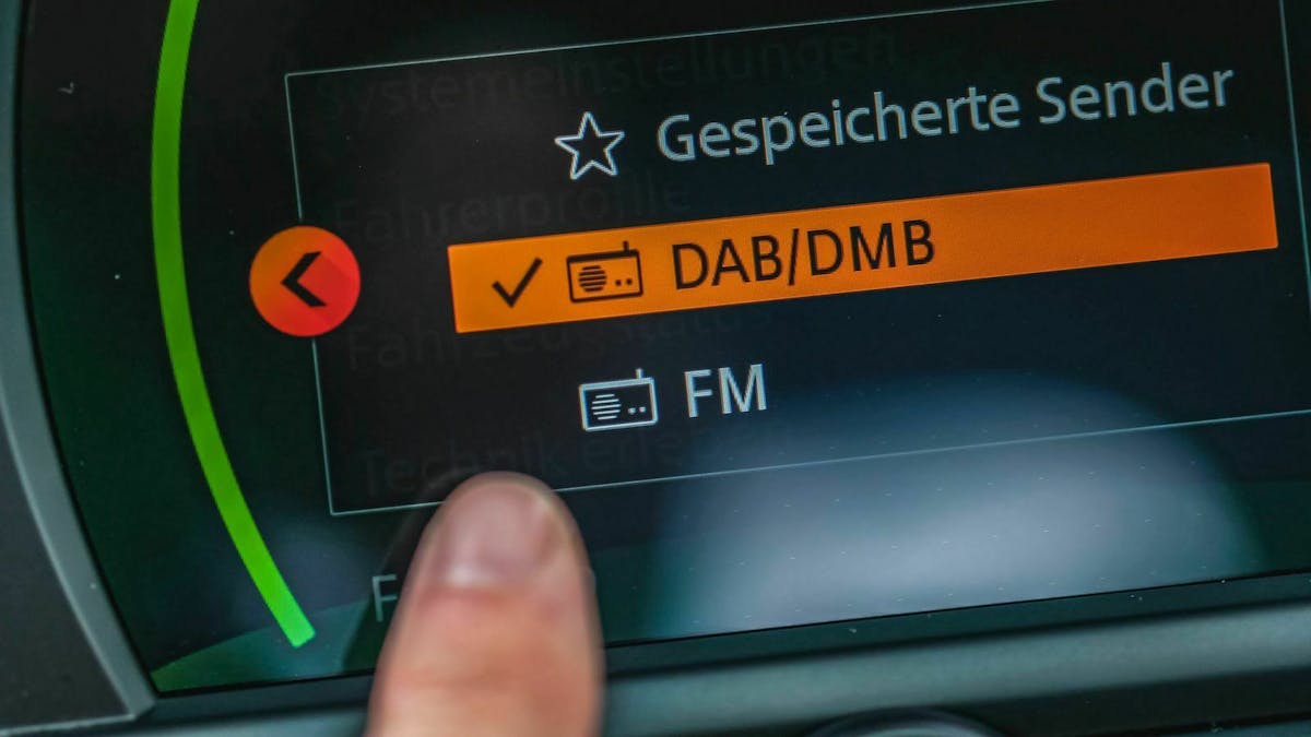 Jemand zeigt auf die aktivierte DAB-Funktion auf dem Display eines Autoradios.
