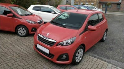 Ein roter Peugeot 108 steht am Straßenrand, im Hintergrund stehen fünf weitere PKW in verschiedenen Farben