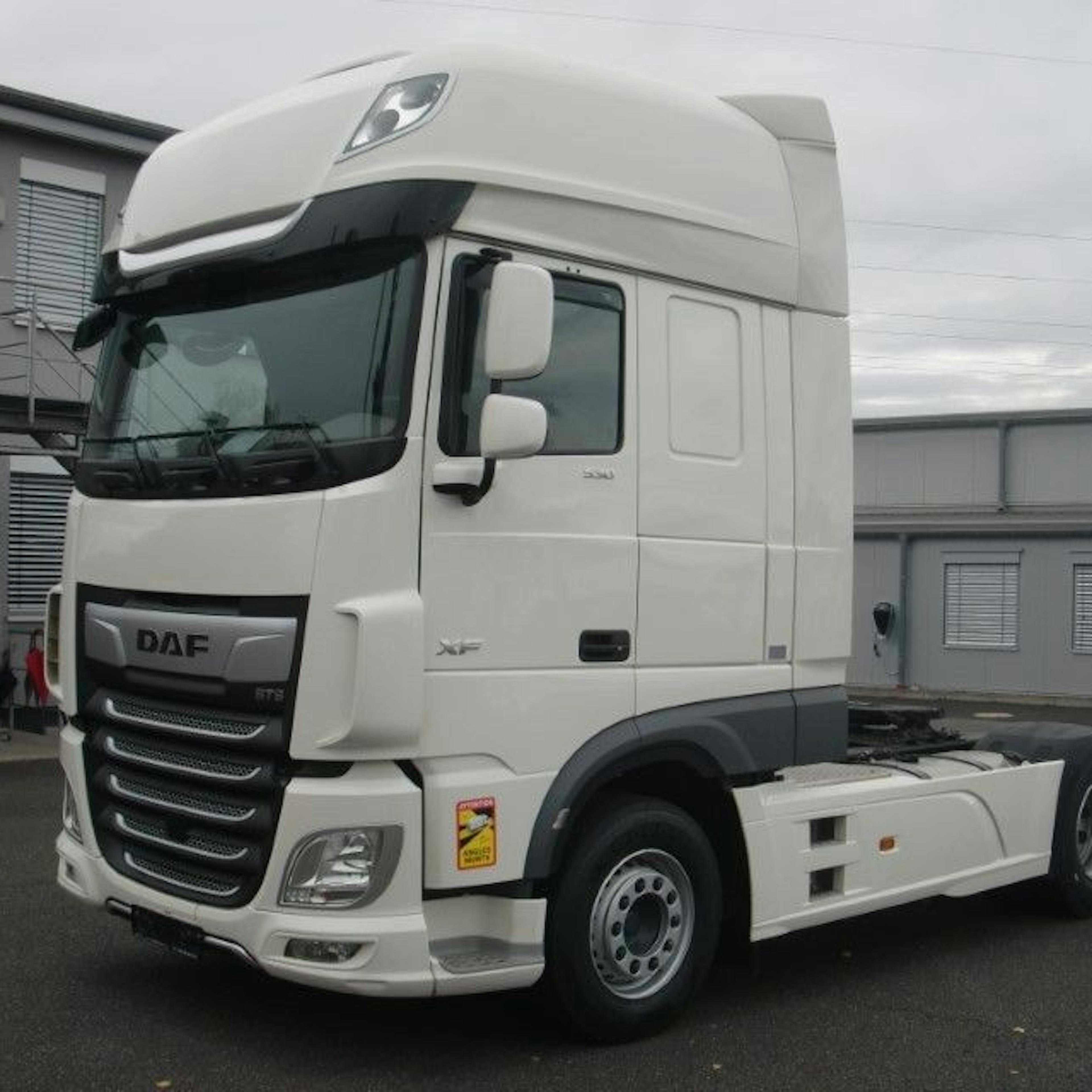 A white DAF tractor-trailer is parked on an asphalt surface