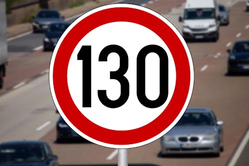 Ein Verkehrsschild zeigt ein Tempolimit von 130 km/h, aufgestellt neben einer mehrspurigen Autobahn. Im Hintergrund fahren mehrere Fahrzeuge.