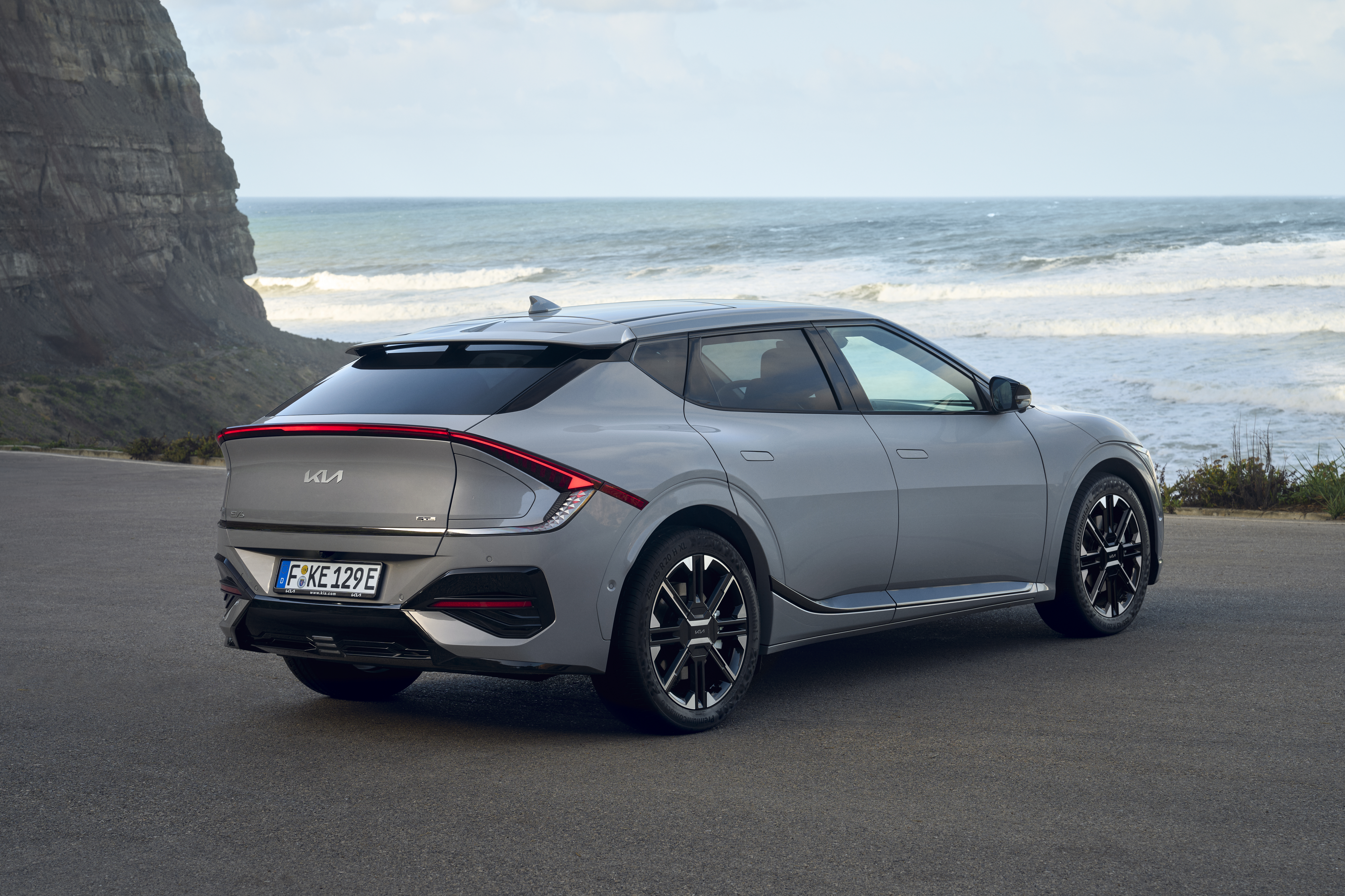 Gray Kia EV6 facelift in the rear view, standing in front of the sea.