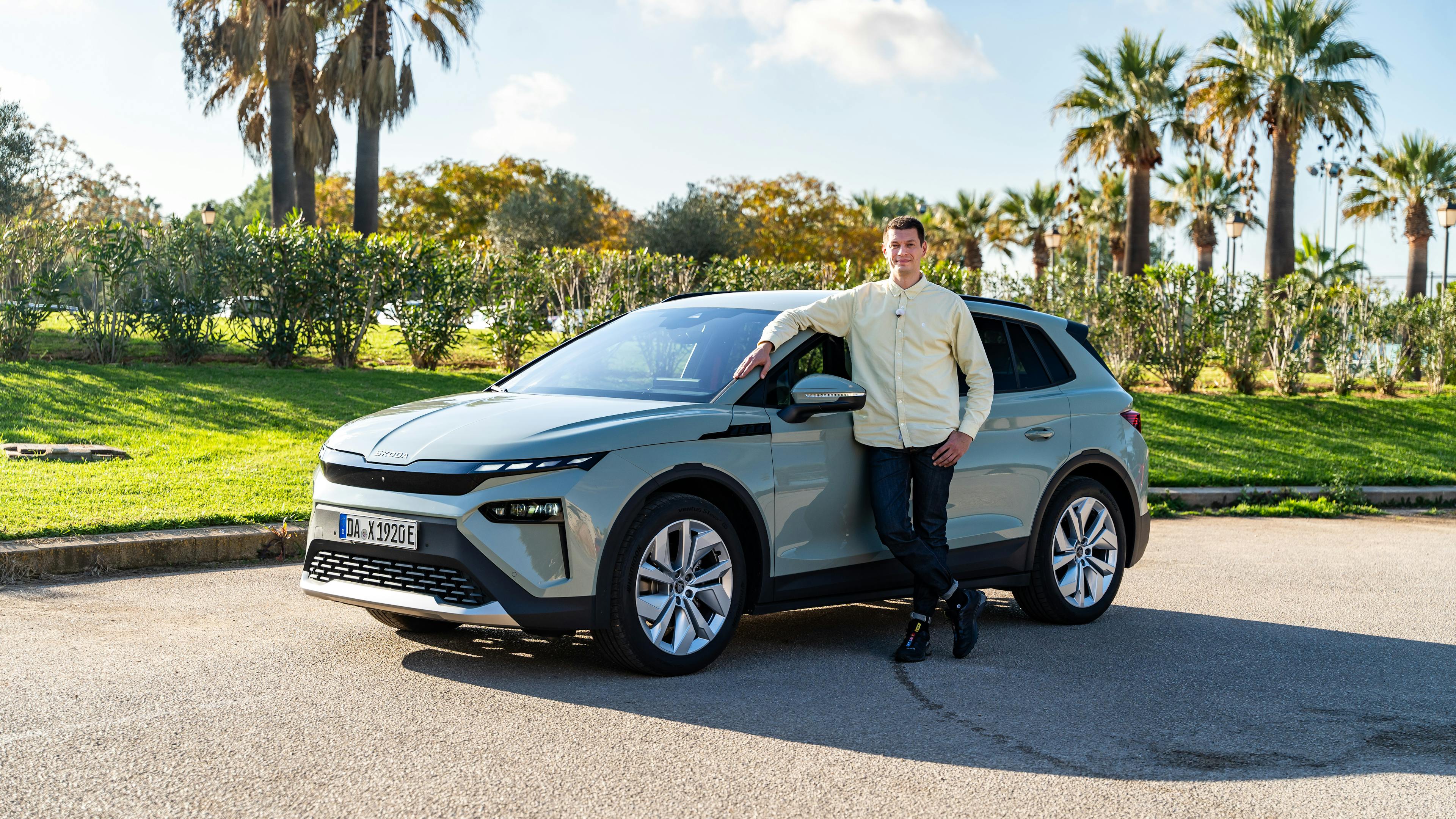White-gray Å koda Elroq with an editor standing next to the car.