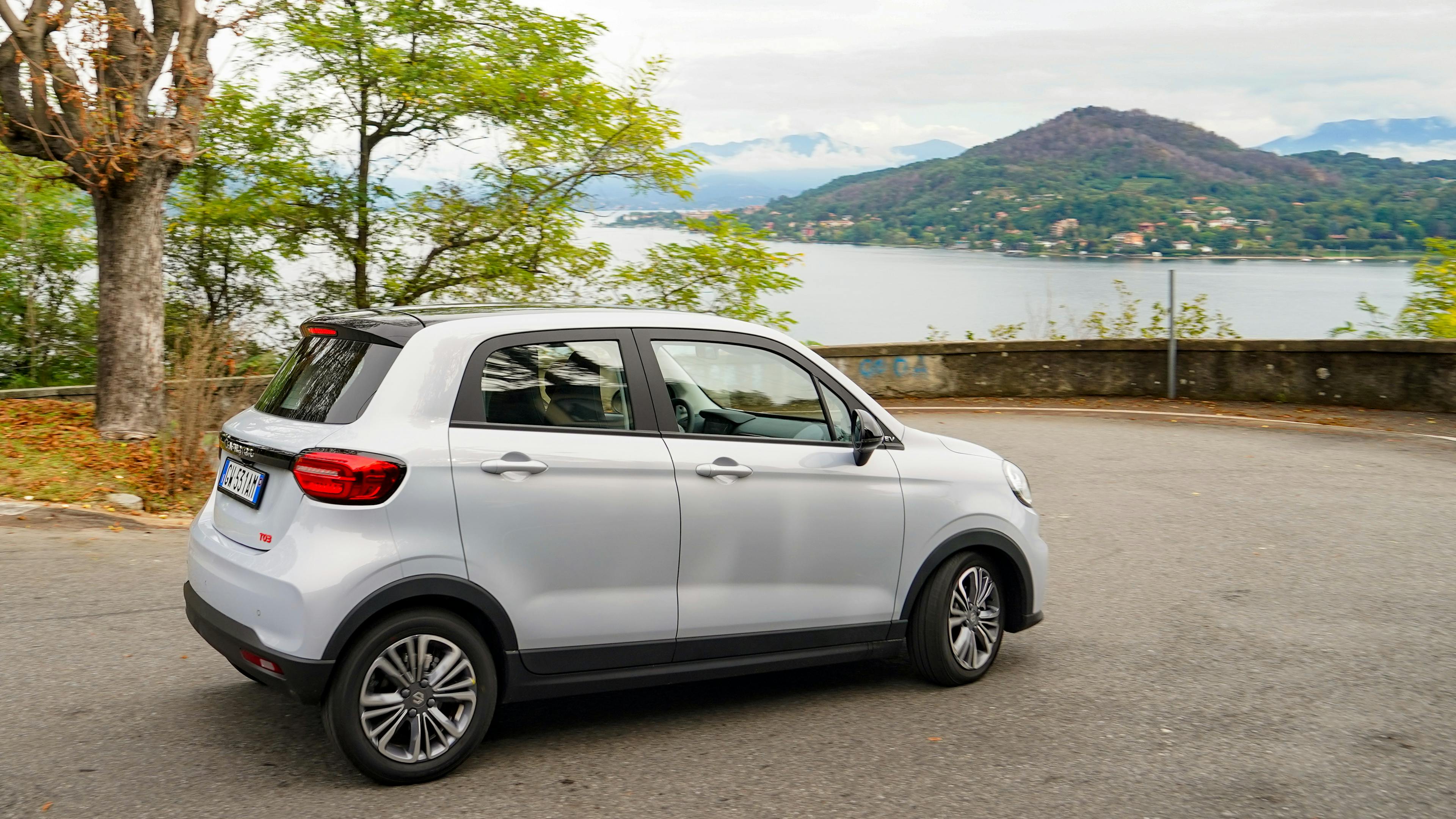 A white Leapmotor T03 stands in a curve in front of a lake.