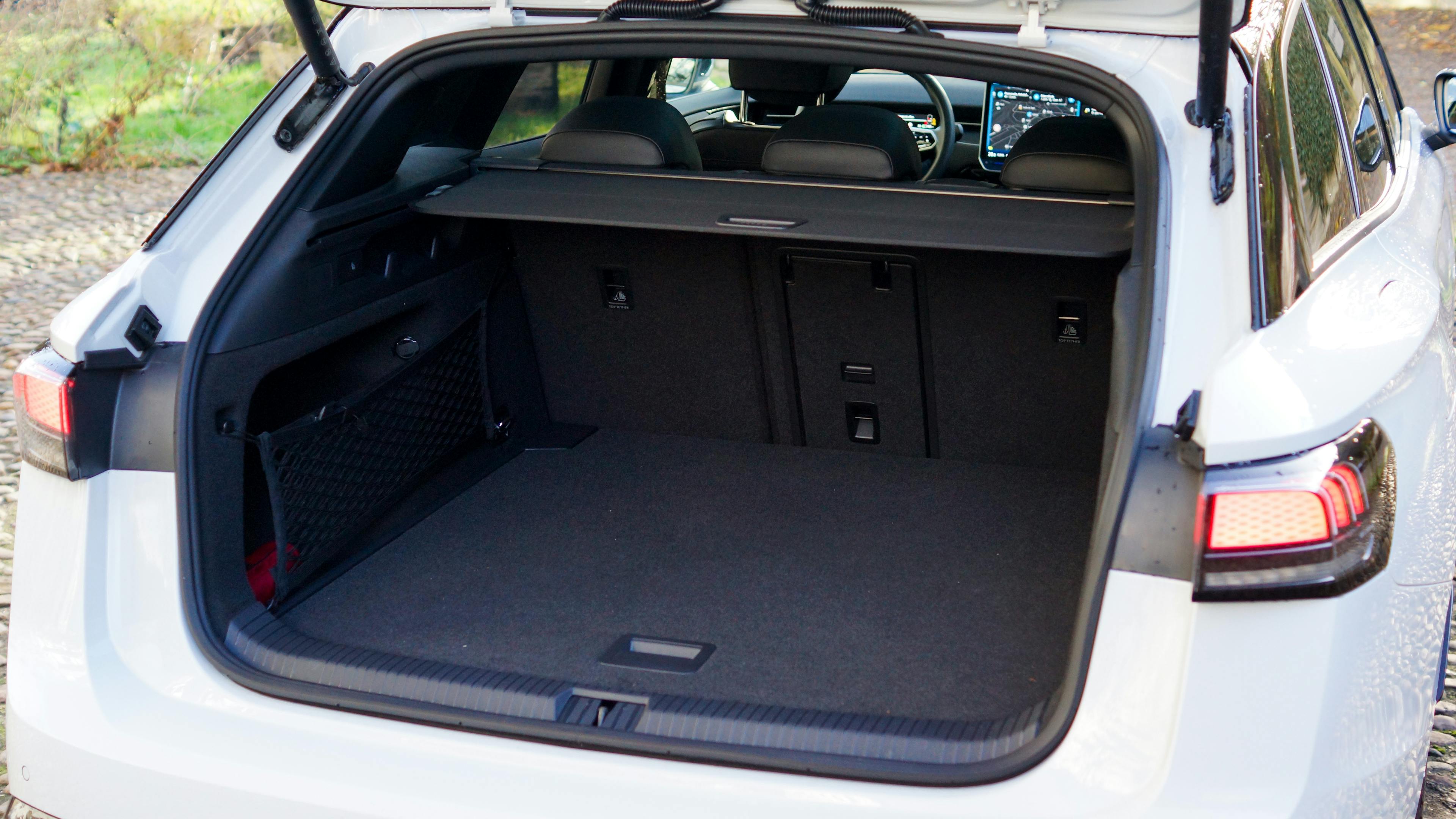 The trunk of a white VW ID.7 Tourer, open and empty, shows generous storage space.