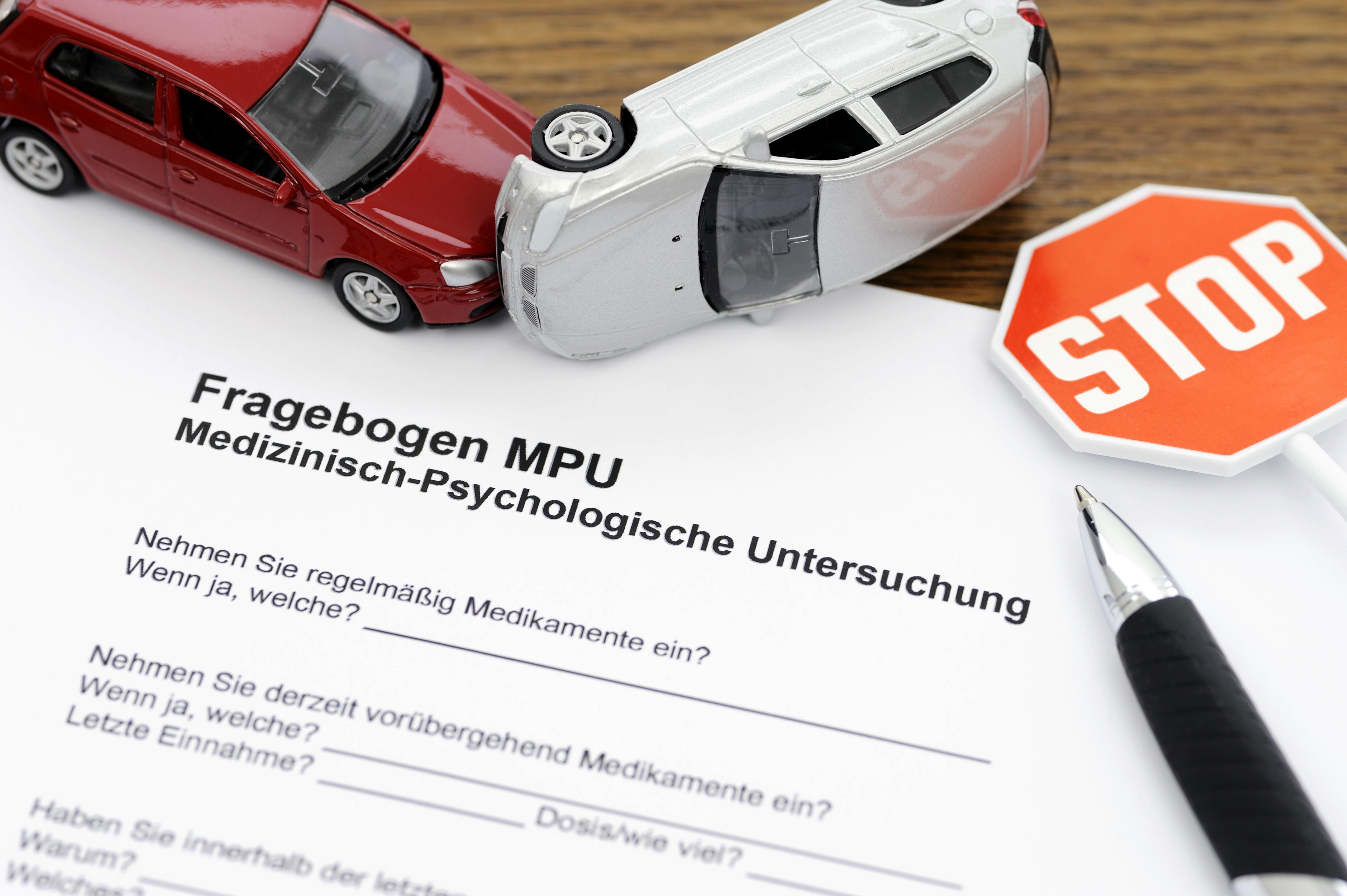 Ein Fragebogen zur medizinisch-psychologischen Untersuchung (MPU) liegt auf einem Tisch, umgeben von Spielzeugautos und einem Stoppschild.