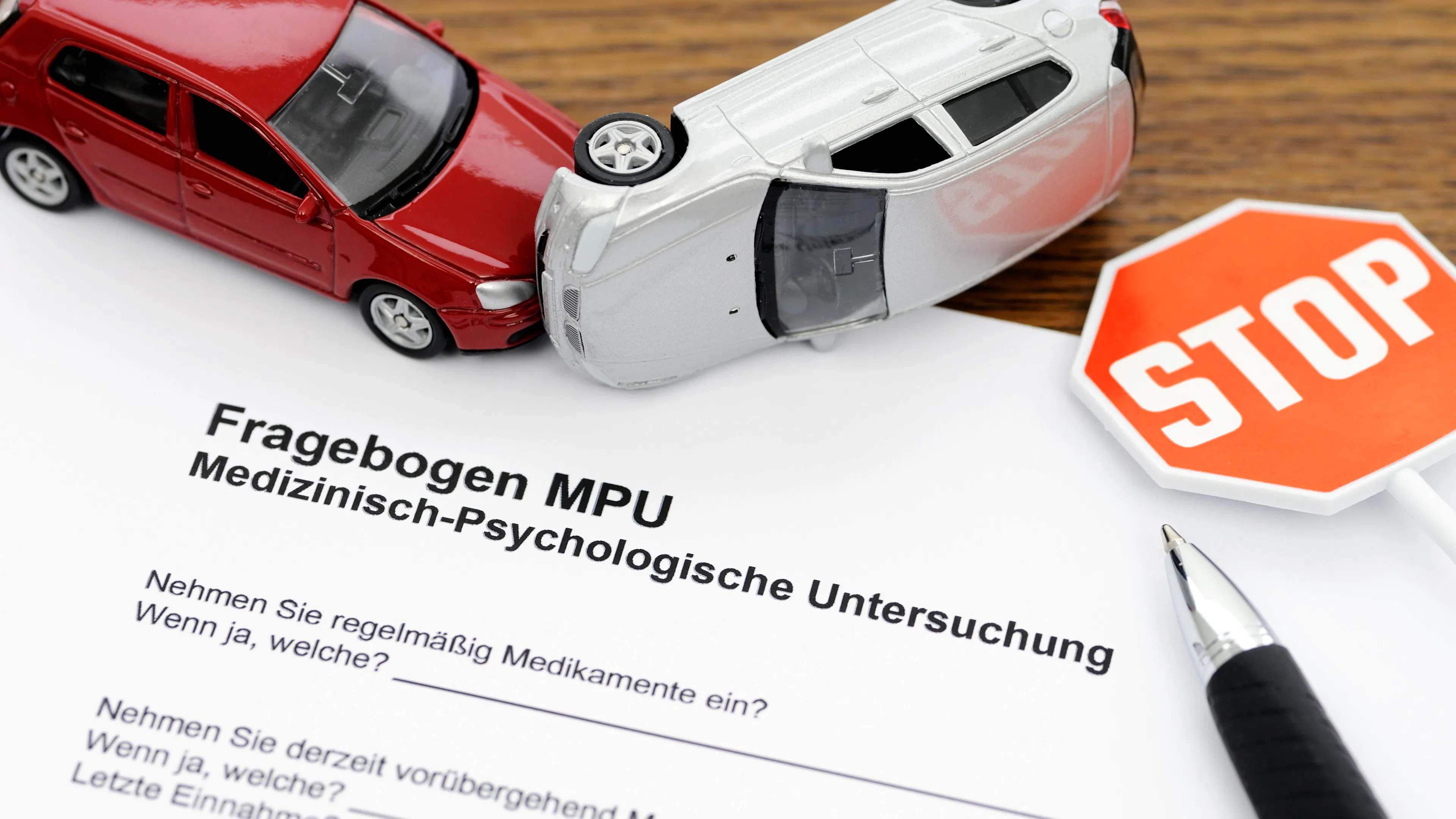 Ein Fragebogen zur medizinisch-psychologischen Untersuchung (MPU) liegt auf einem Tisch, umgeben von Spielzeugautos und einem Stoppschild.