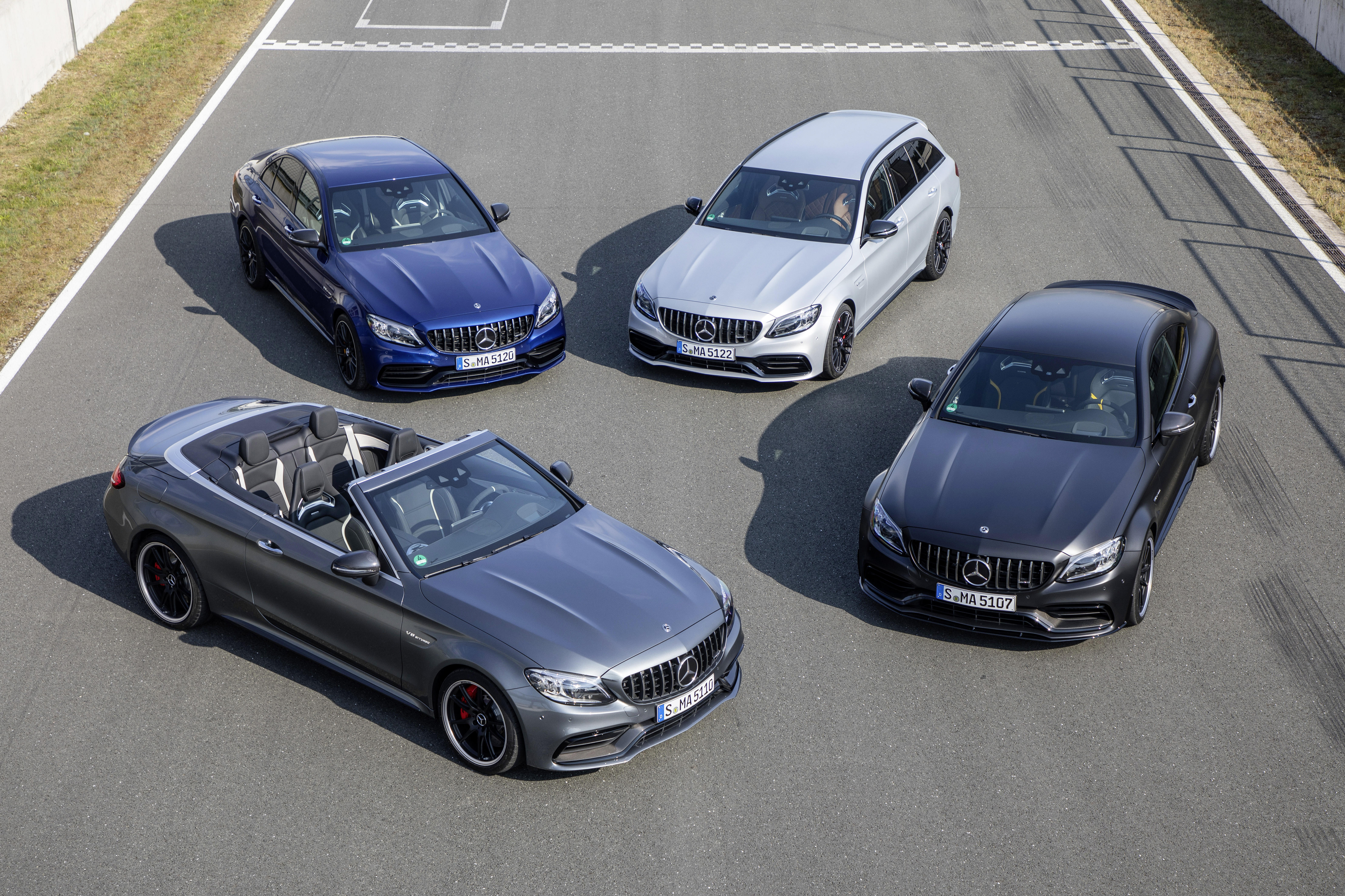 Vier Karosserievarianten des C63 parken auf einer Rennstrecke.