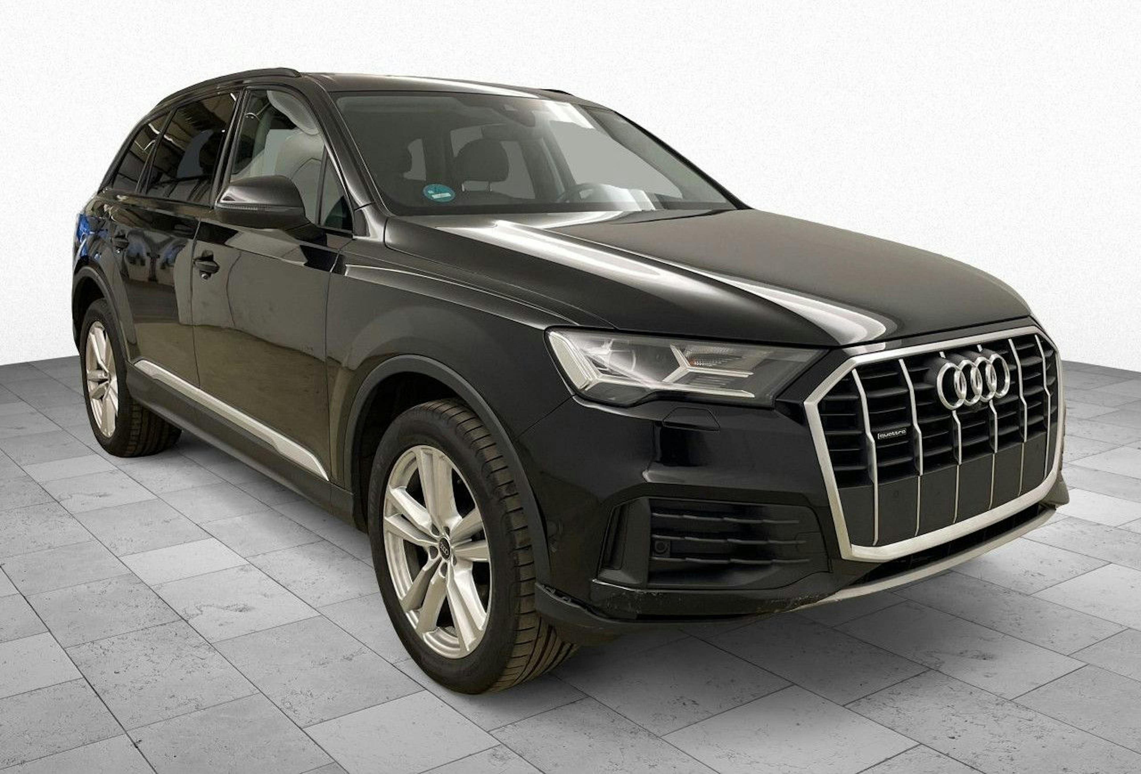 Schwarzer Audi SUV steht auf grauem Boden, seitliche Vorderansicht, mit markantem Kühlergrill und eleganten Linien, helle Umgebung.