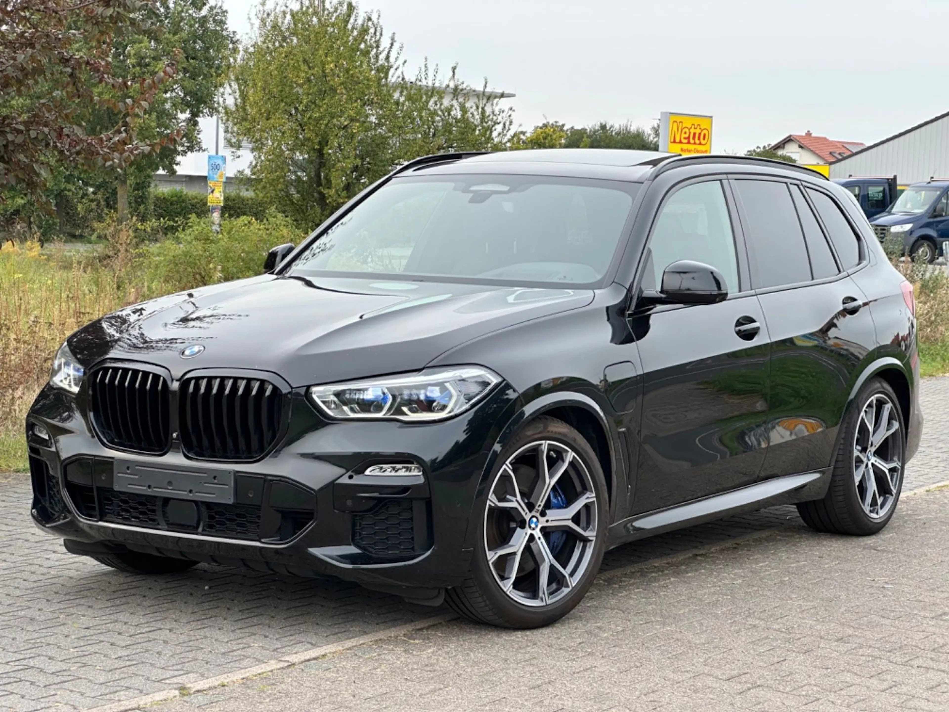 Ein schwarzer BMW X5 von schräg vorn auf einem Parkplatz fotografiert.