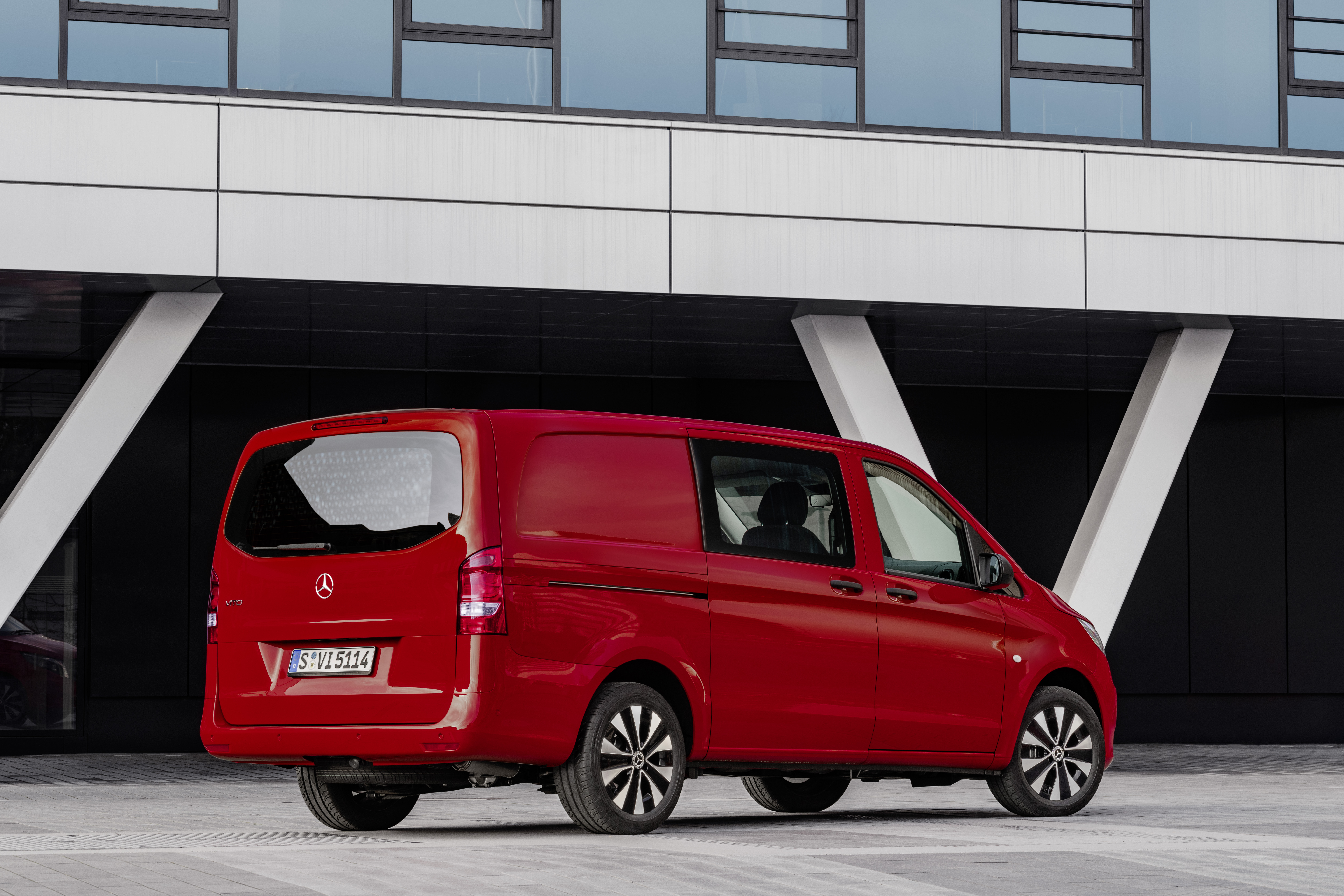 Ein roter Mercedes Vito Mixto parkt vor einem modernen Gebäude.