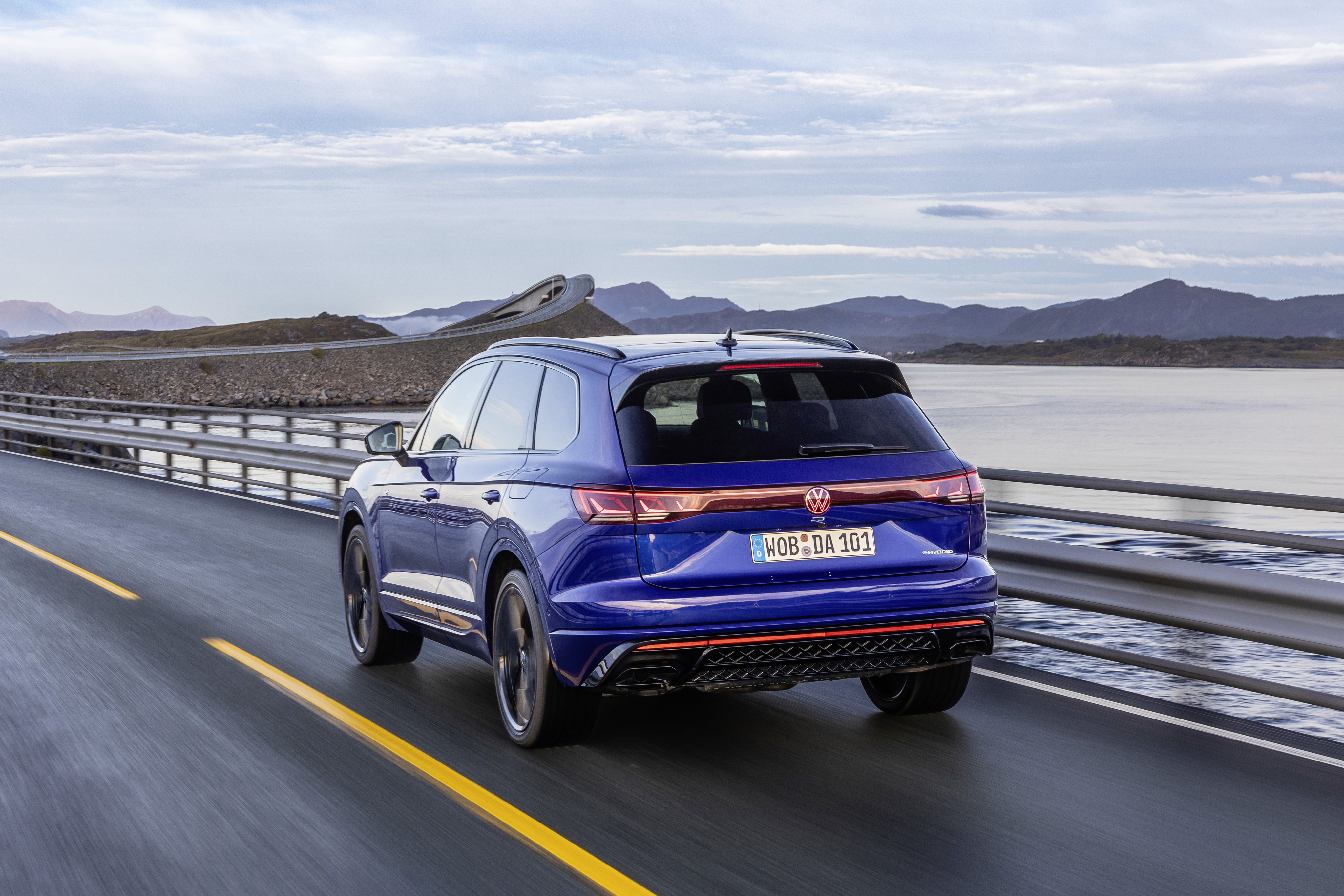 Ein blauer VW Touareg R fährt eine Küstenstraße entlang.