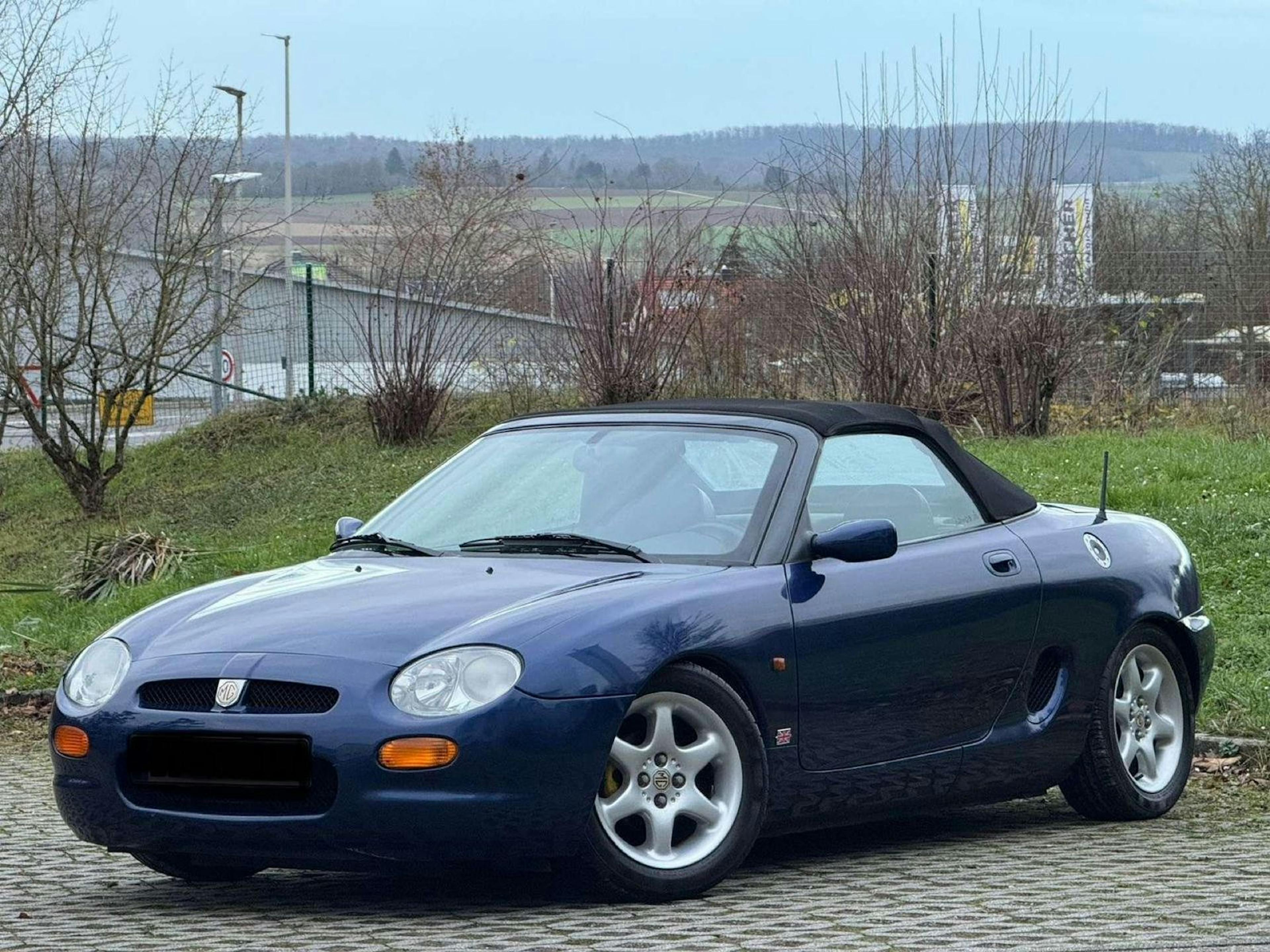 Ein blauer MG F steht auf einem Parkplatz.
