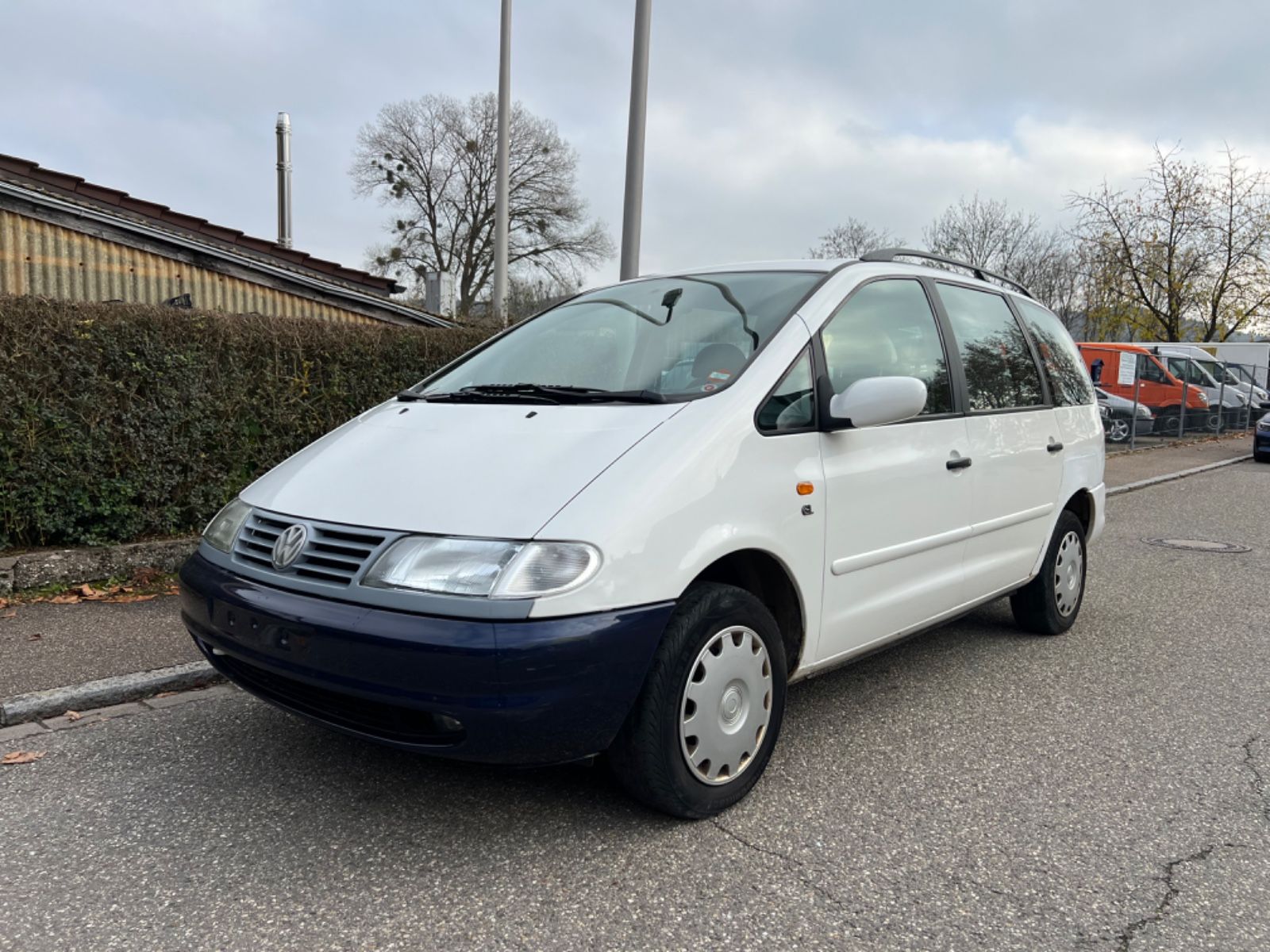 Ein weißer VW Sharan steht an der Straße.