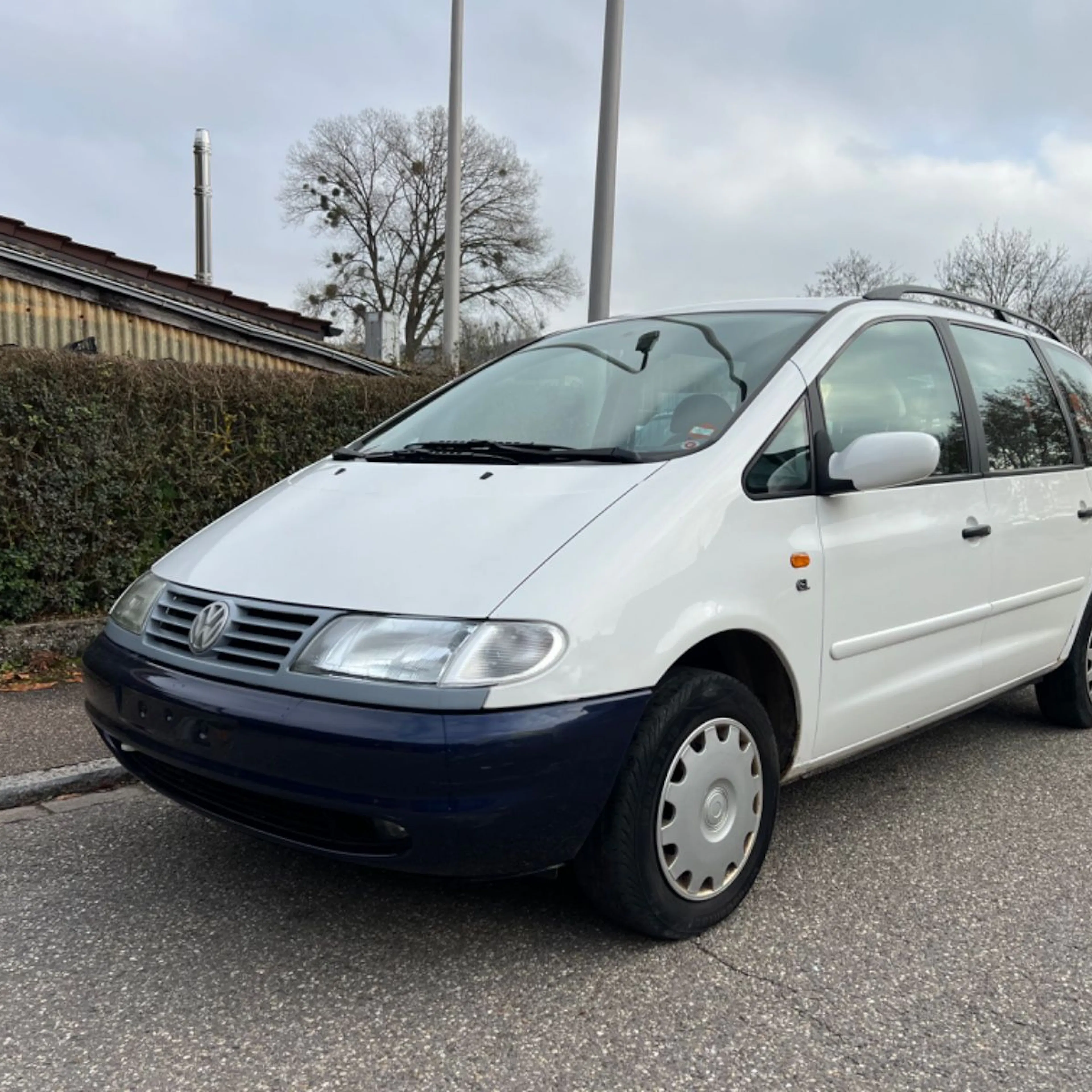 Ein weißer VW Sharan steht an der Straße.