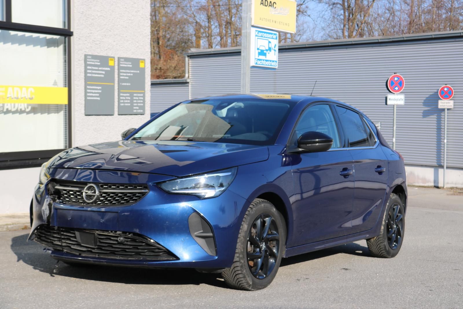 Ein blauer Opel Corsa steht auf dem Hof eines Händlers.