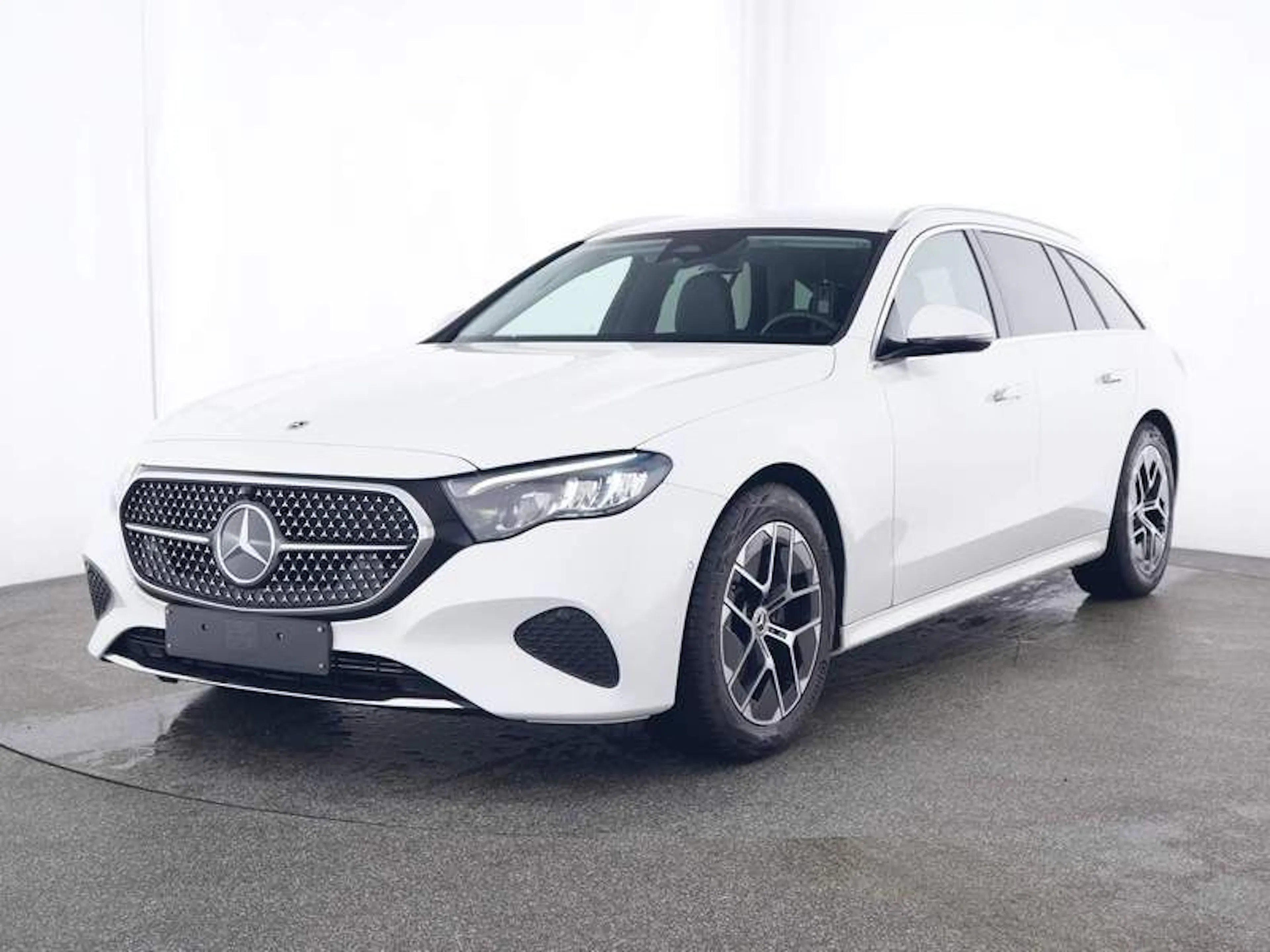 Ein weißes Mercedes E-Klasse T-Modell steht in der Halle eines Händlers.