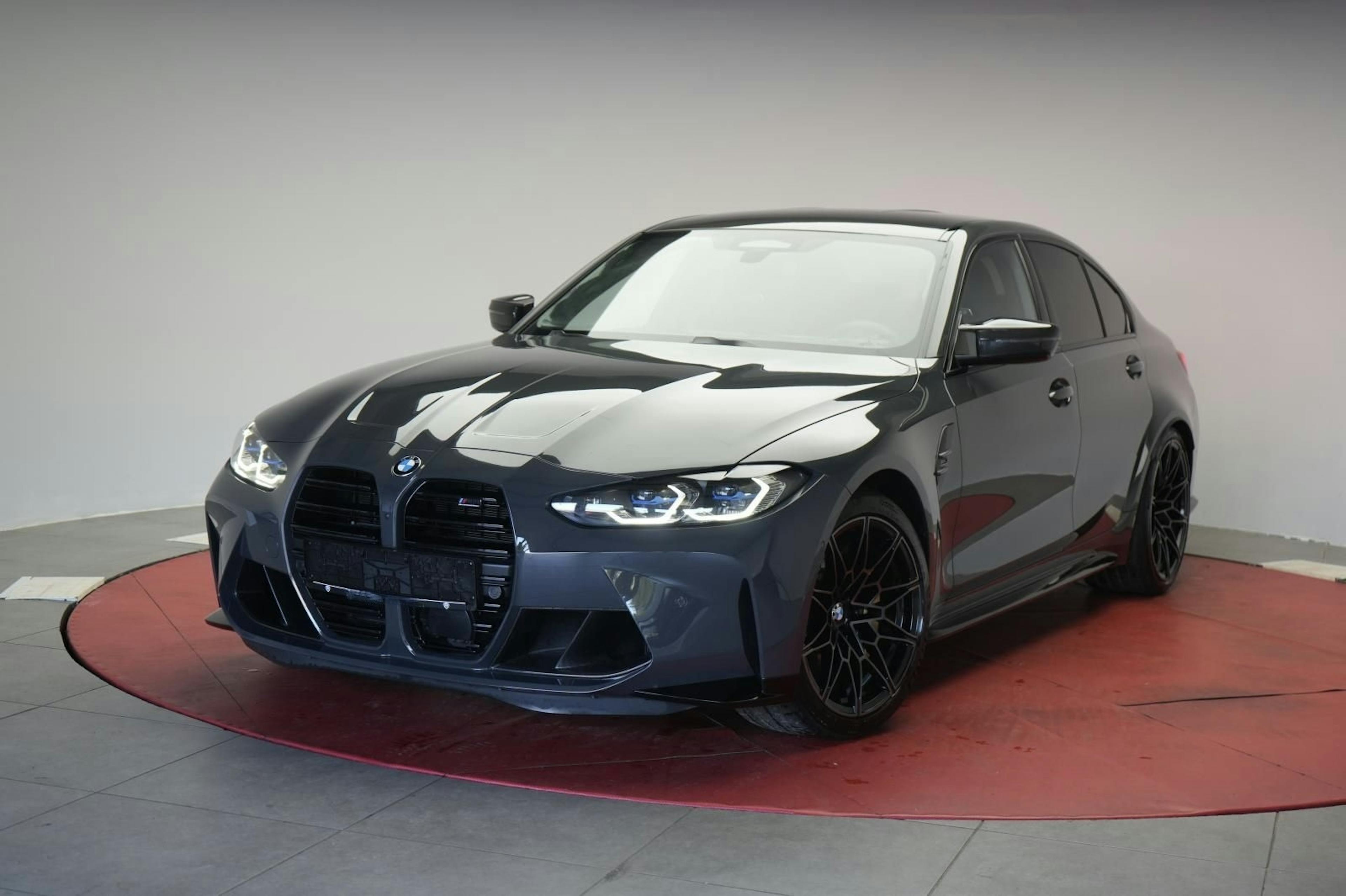 Ein dunkelgrauer BMW M3 steht in einem Verkaufsraum.