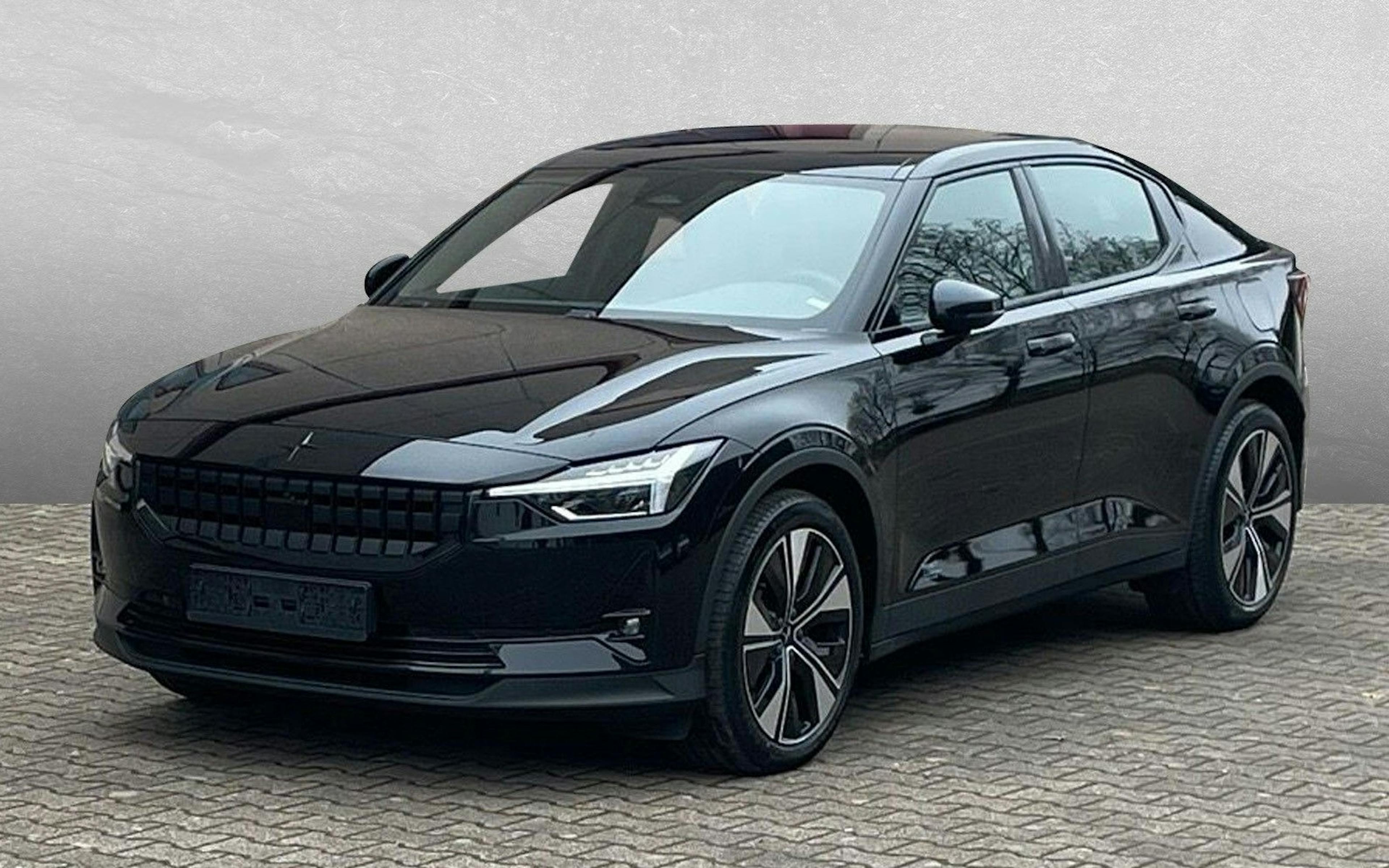 Frontalansicht eines schwarzen Polestar 2 mit markantem Kühlergrill und LED-Scheinwerfern, aufgenommen auf einem Parkplatz bei Tageslicht