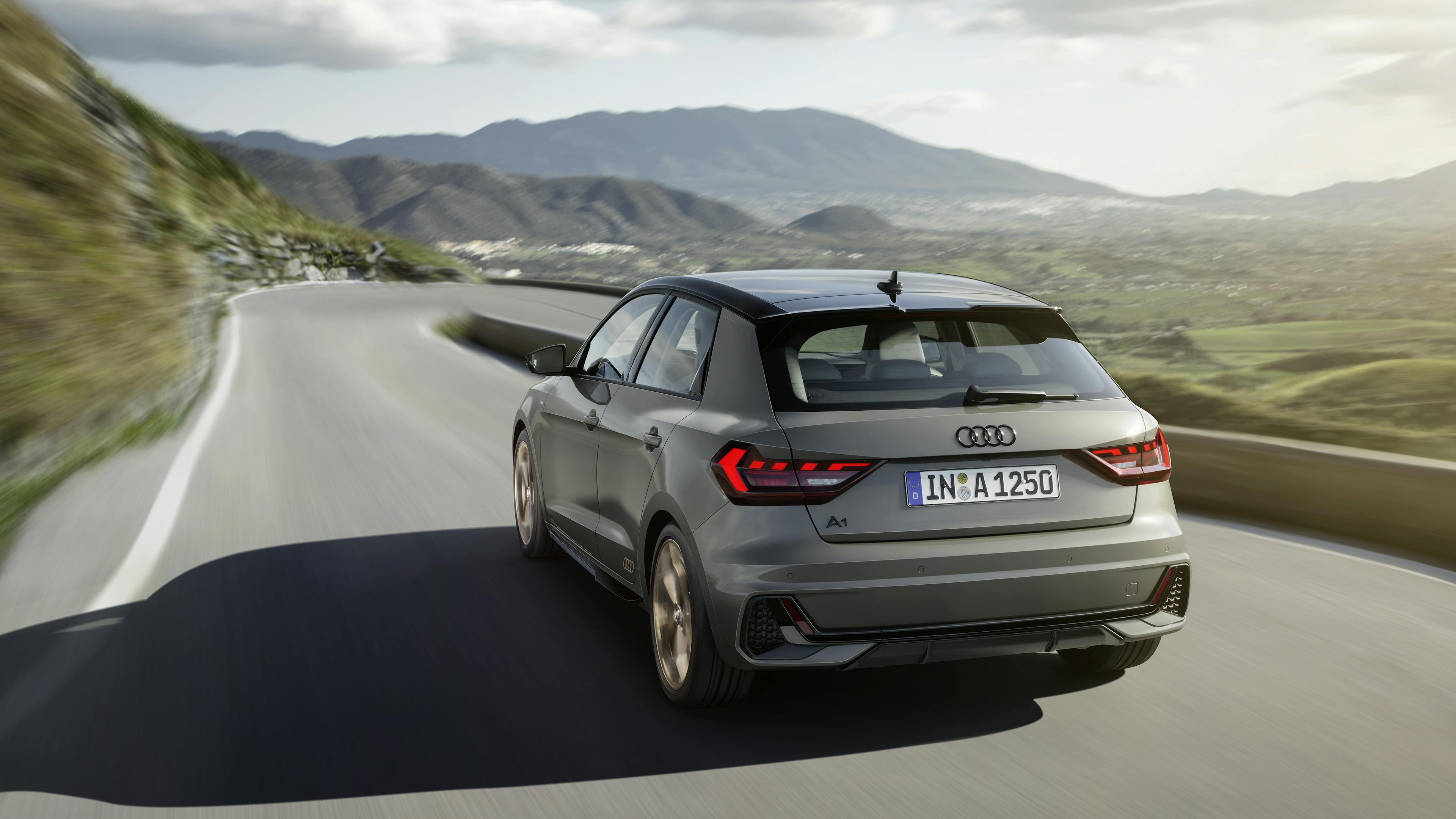 Ein grauer Audi A1 fährt auf einer kurvigen Gebirgsstraße.