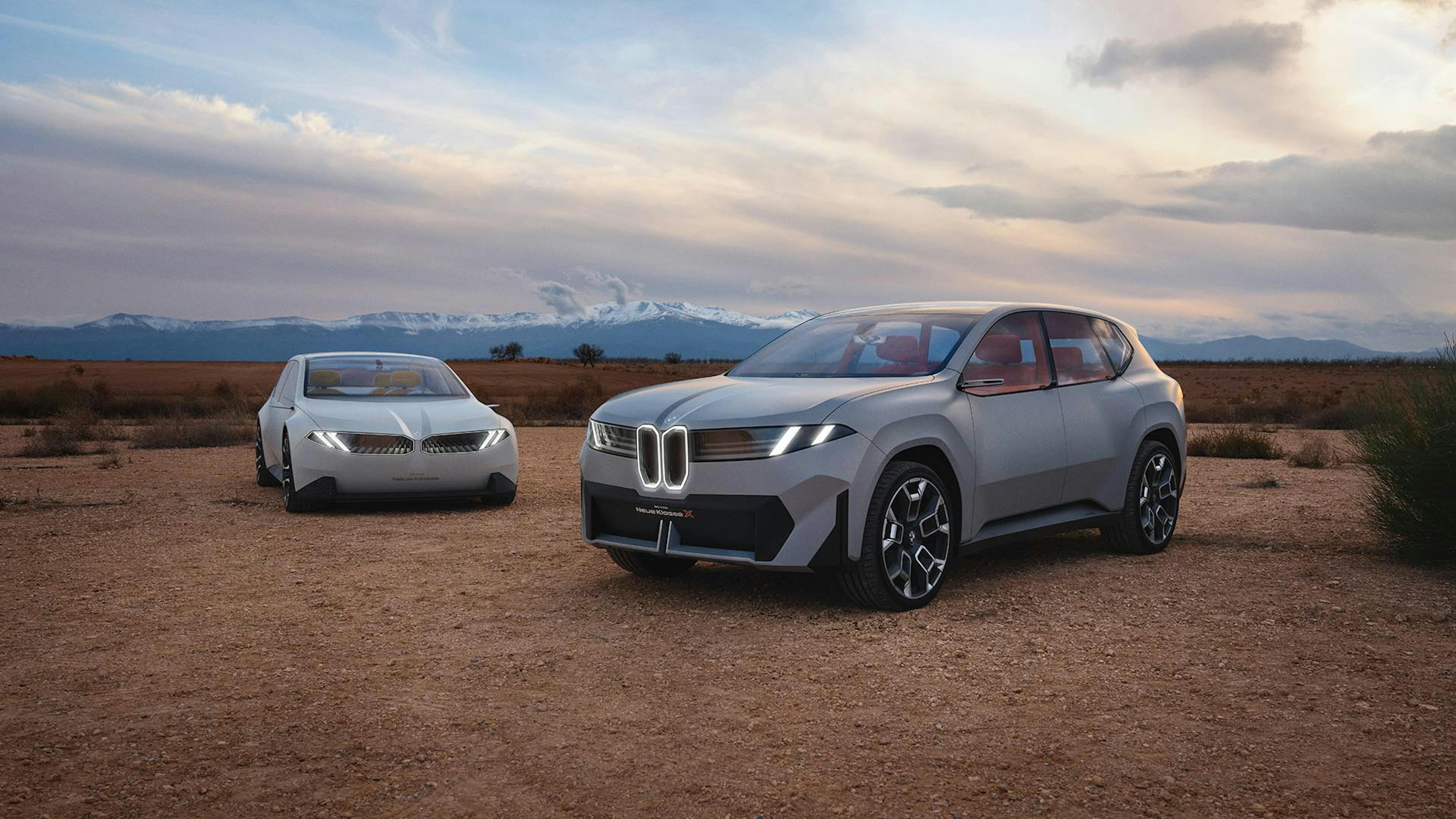 Die Studien BMW Neue Klasse X und Neue Klasse parken nebeneinander in der Wüste.