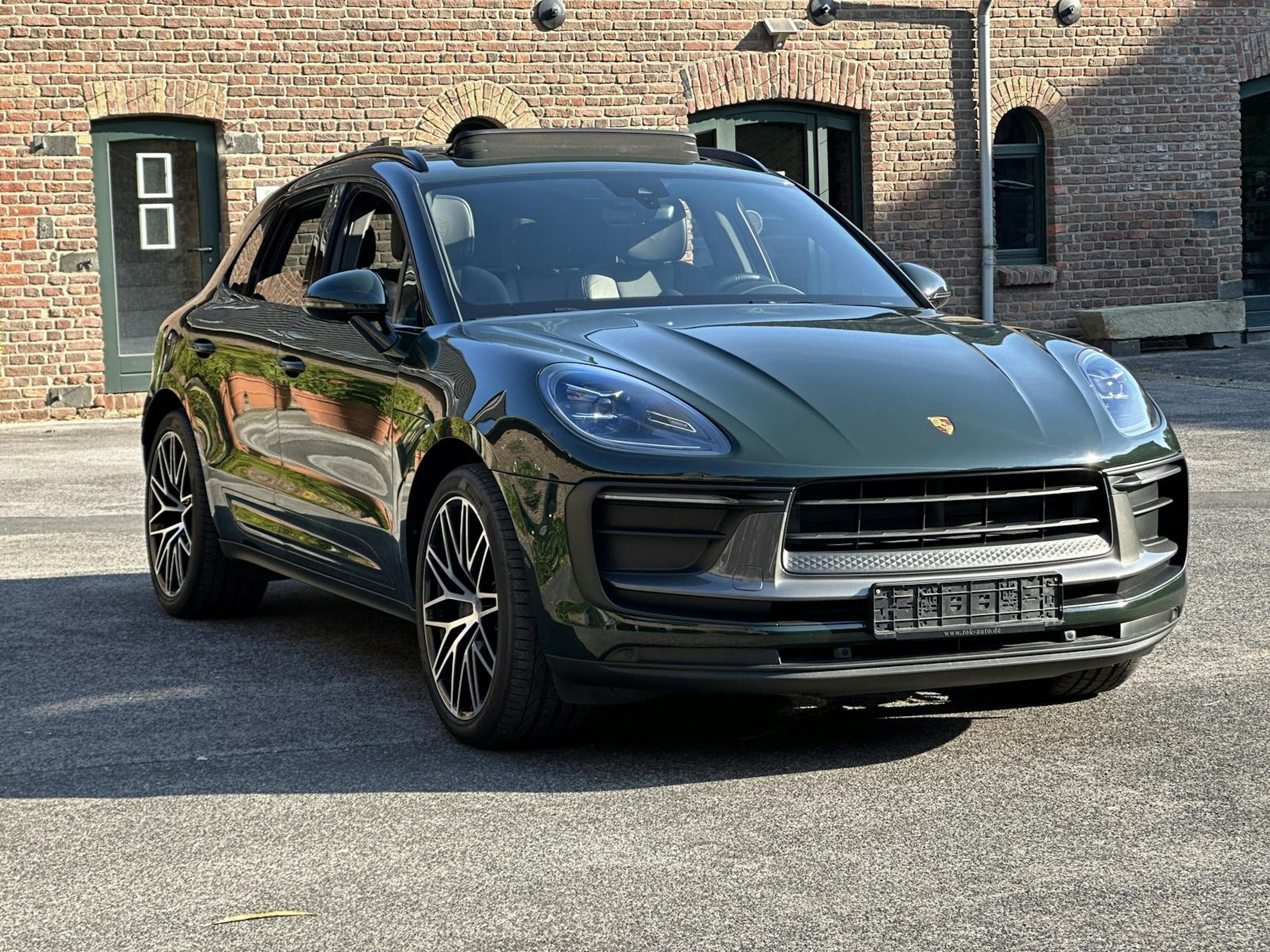 Ein Porsche Macan steht vor einem Haus aus roten Ziegelsteinen.
