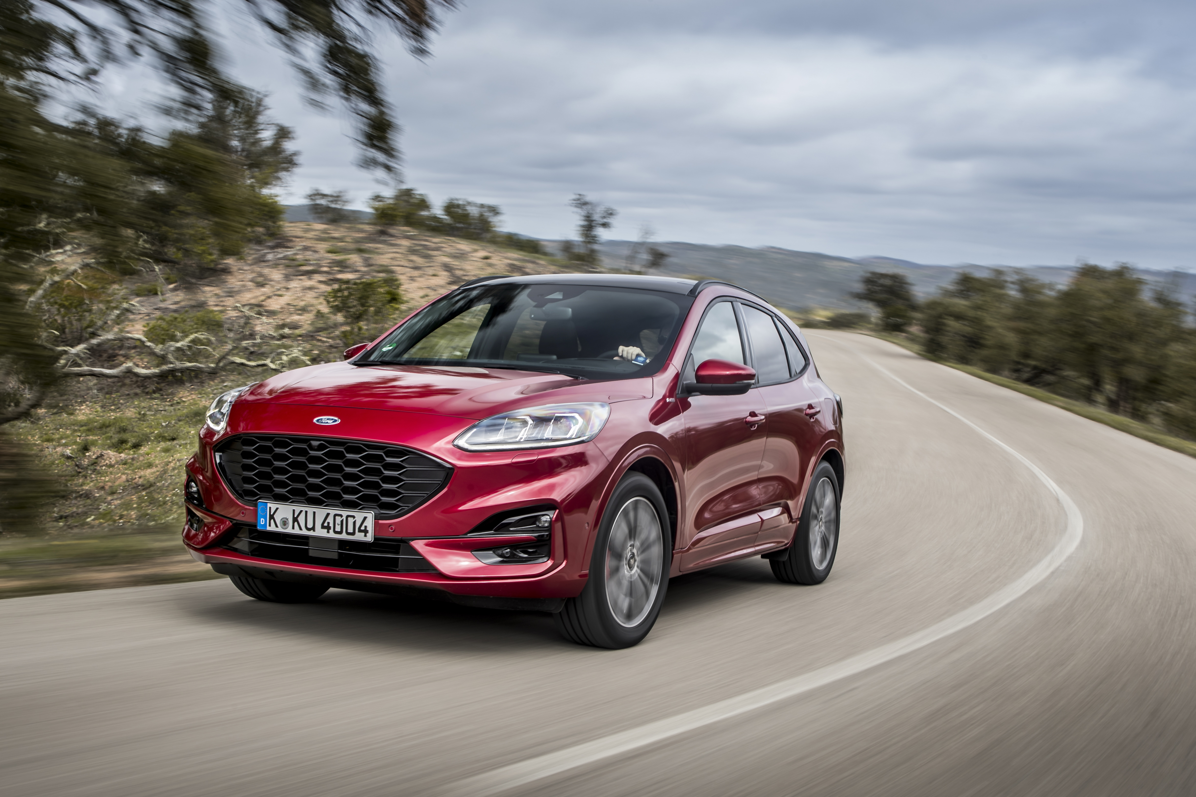 Ein roter Ford Kuga fährt auf einer kurvigen Gebirgsstraße.