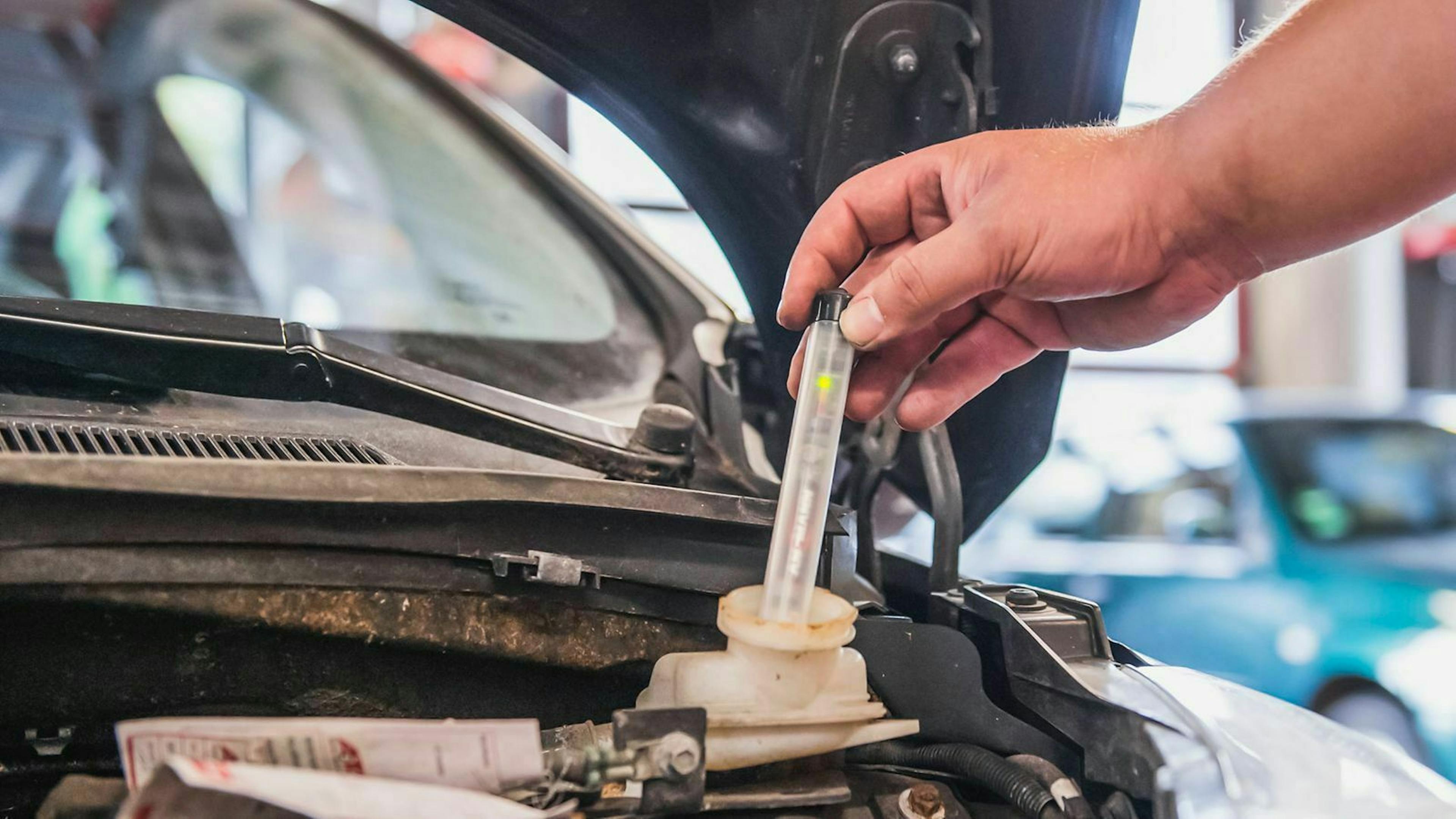 Jemand mit mit einem elektronischen Bremsflüssigkeitstester den Wassergehalt im Betriebsmittel der Bremse