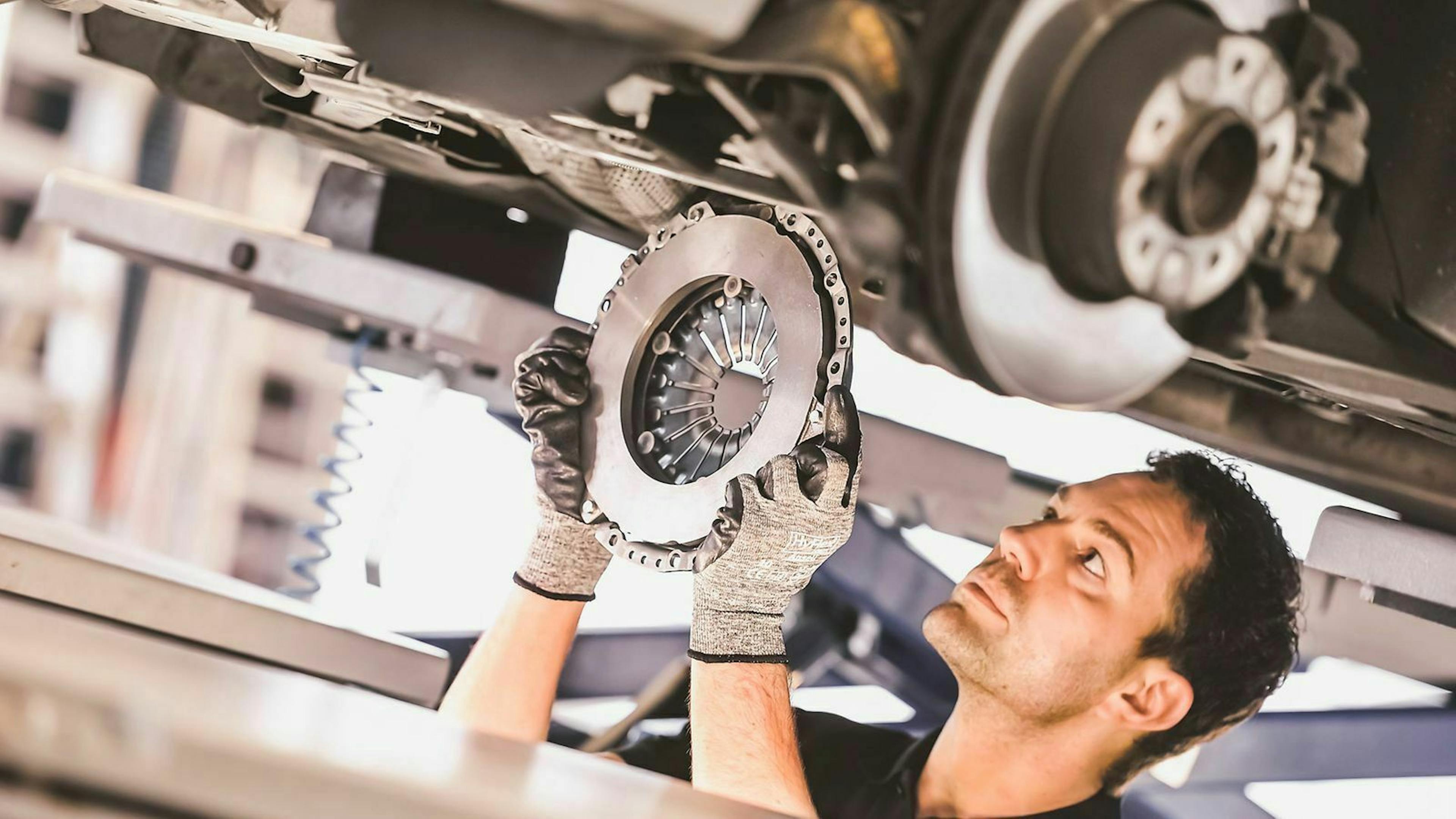 Ein Mechaniker montiert eine neue Kupplung unter einem Auto