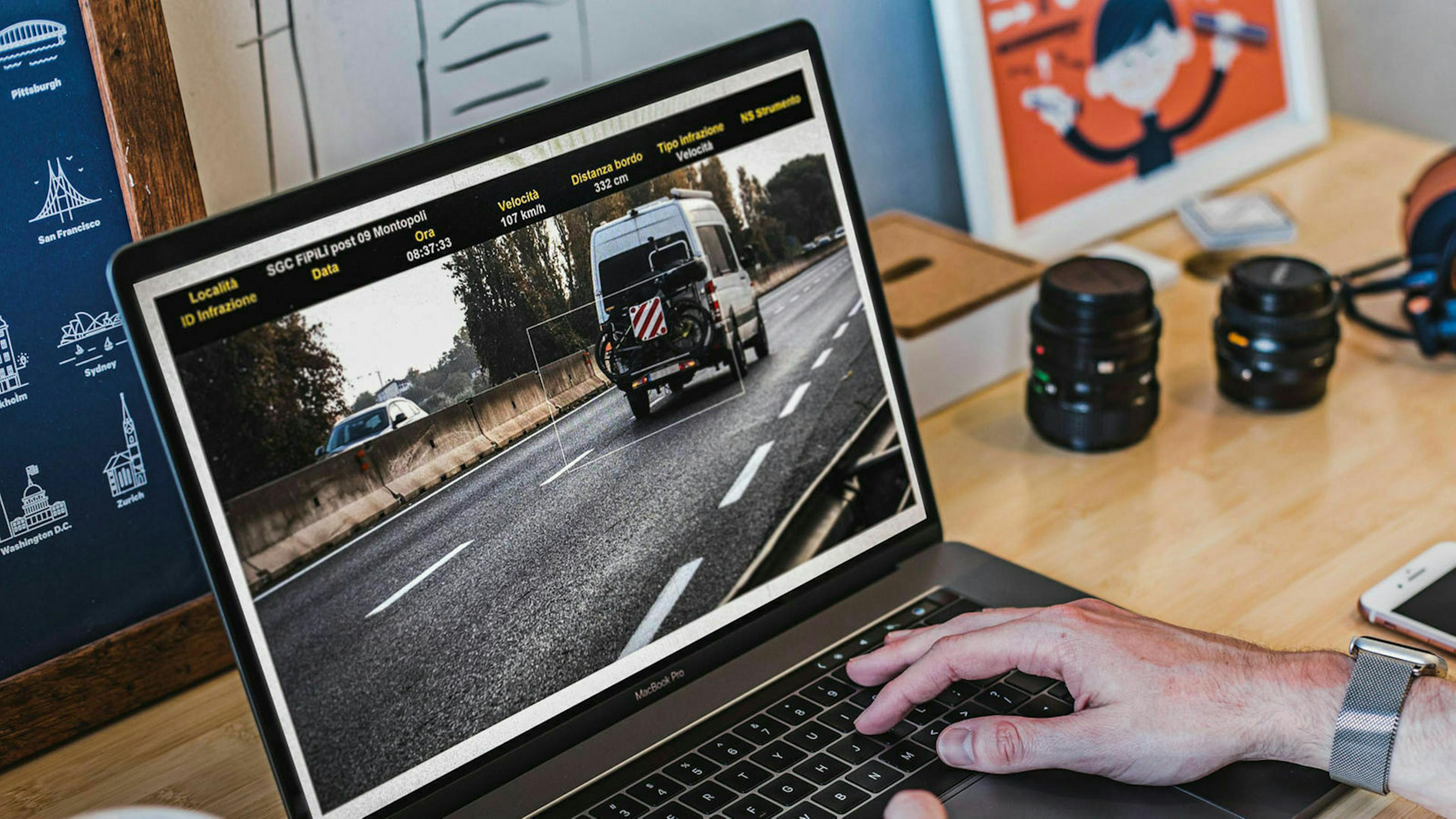 Jemand öffnet auf seinem Laptop den Bußgeldbescheid aus dem Ausland und überprüft das angehängte Foto