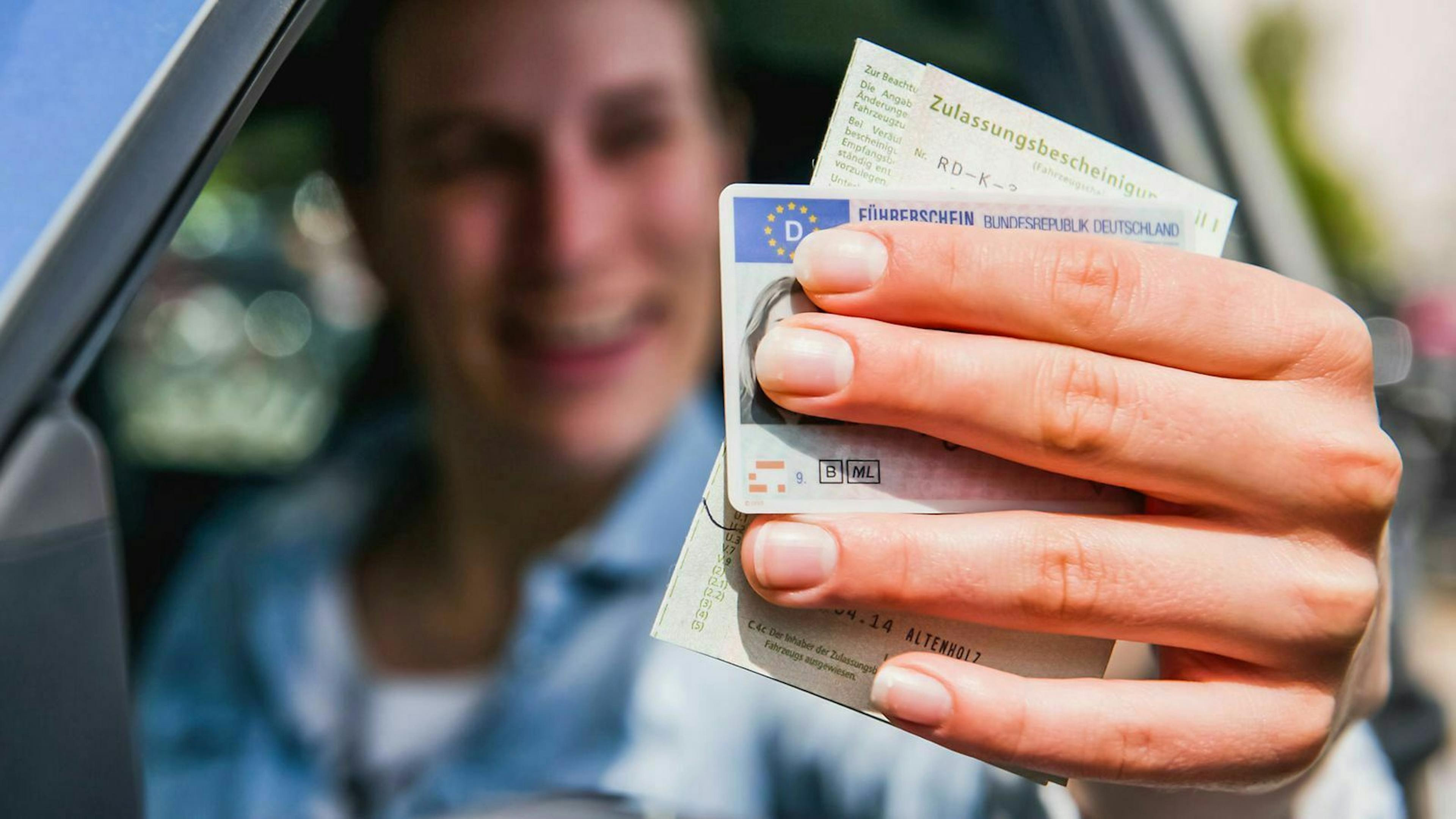 Ein Mann hält Führerschein und Fahrzeugpapiere in die Kamera.