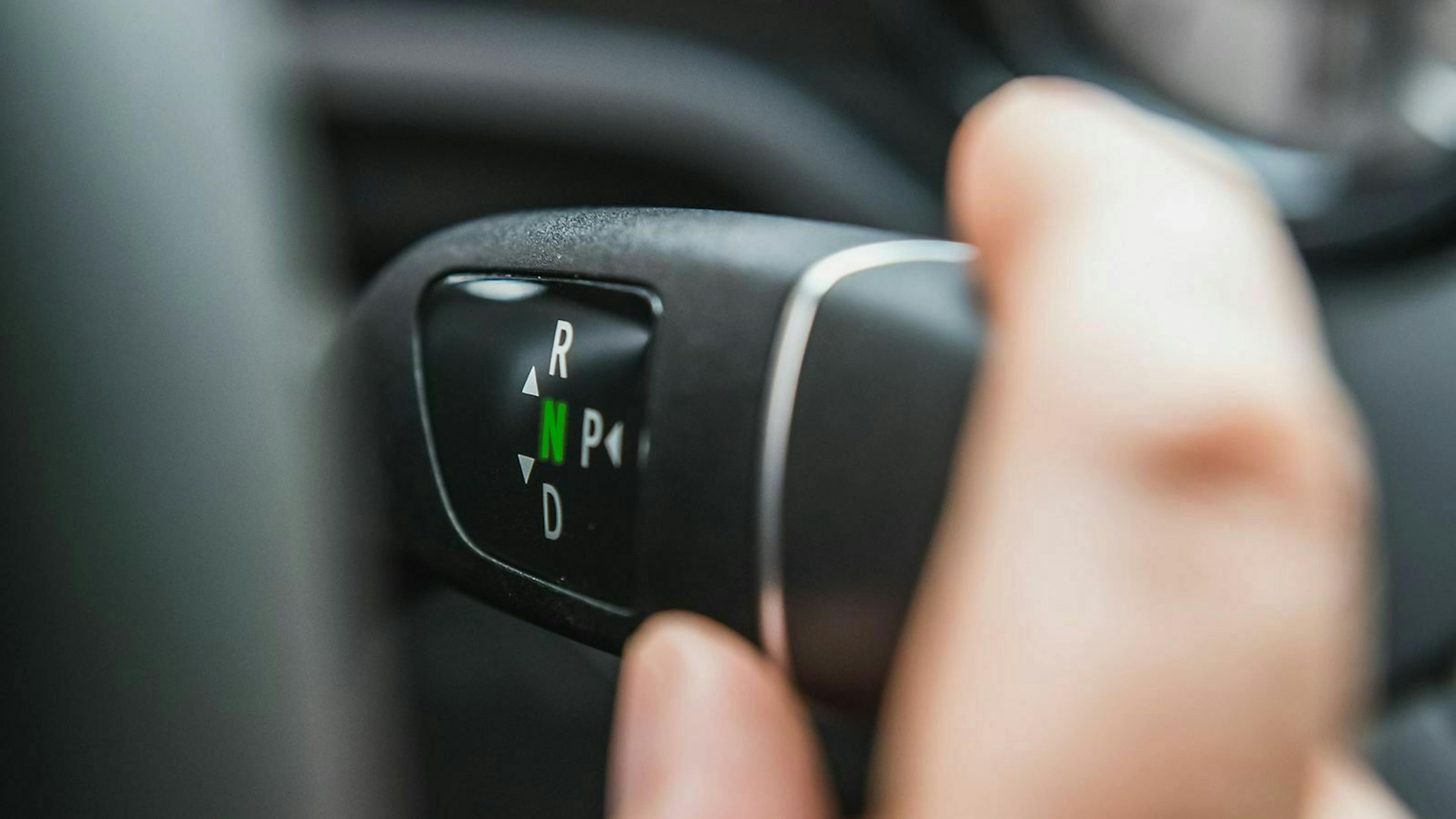 Eine Hand bedient einen Automatikwählhebel und schaltet ihn auf "N".