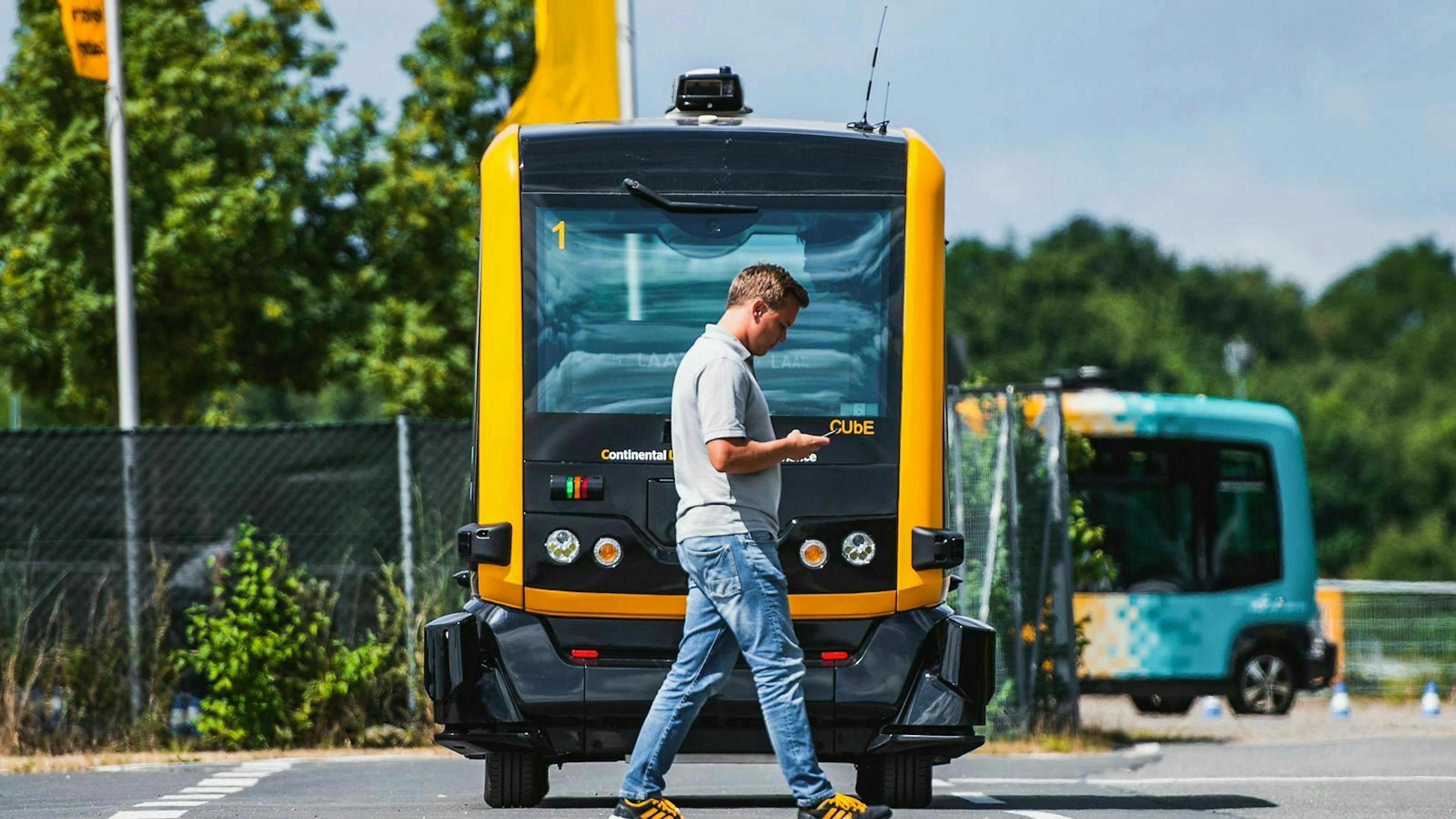 Auf einem Testgeländefährt der autonome Kleinbus Cube von Continental auf einen Mann zu.