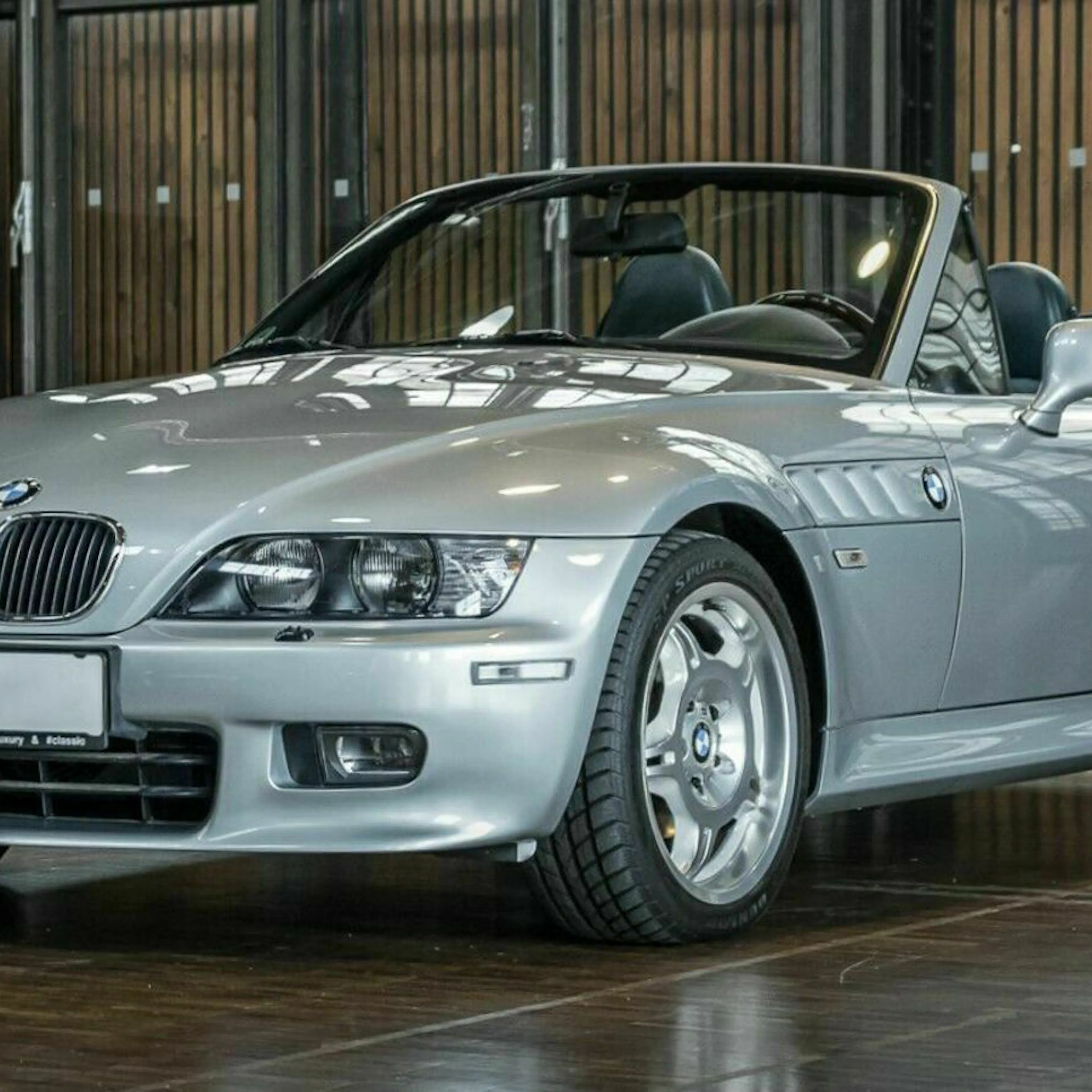 Ein silberner BMW Z3 Oldtimer steht in einem dunklen Raum.