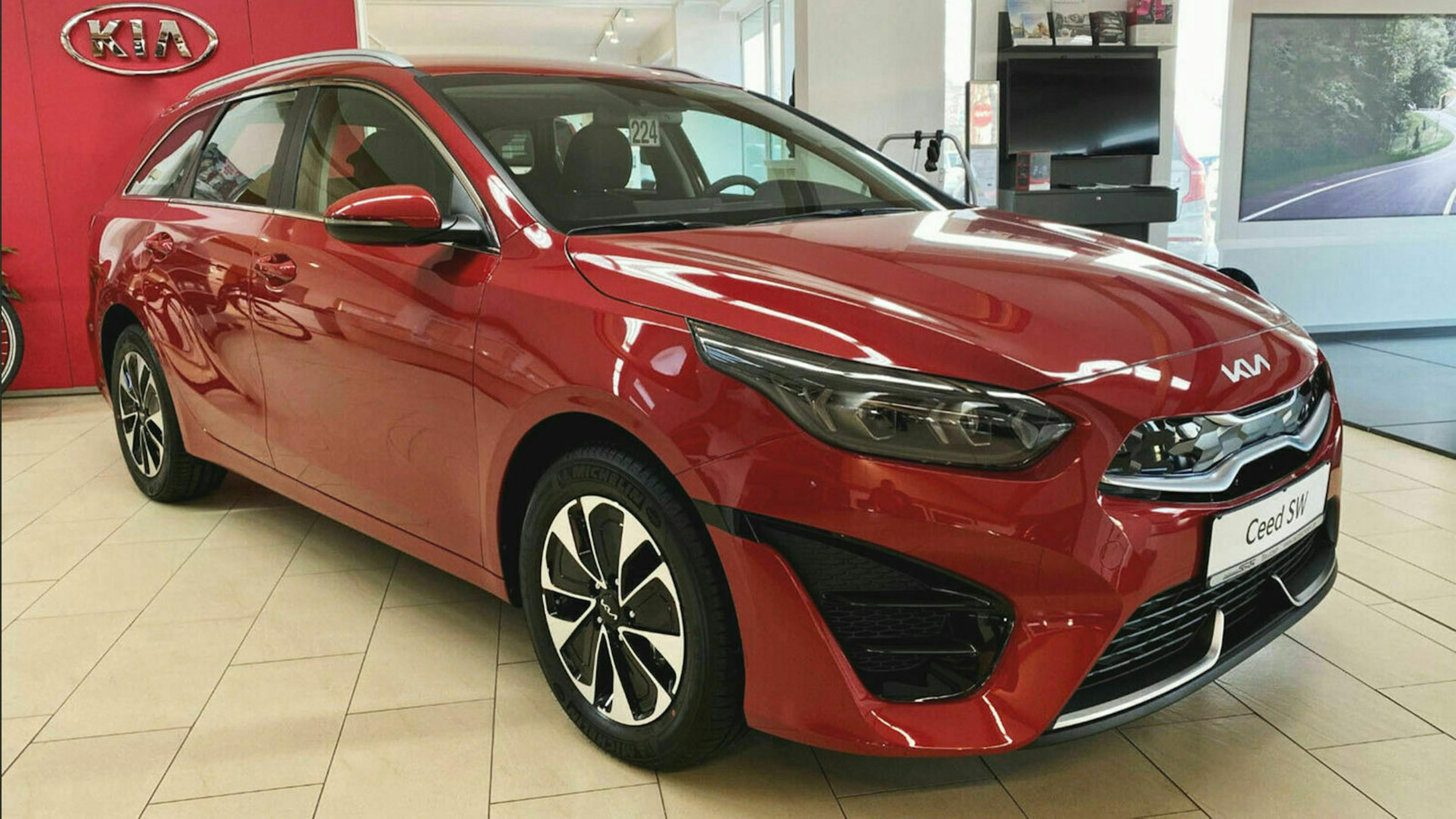 Ein roter Kia Ceed Sortswagon 1.6 GDI steht im Showroom eines Autohauses