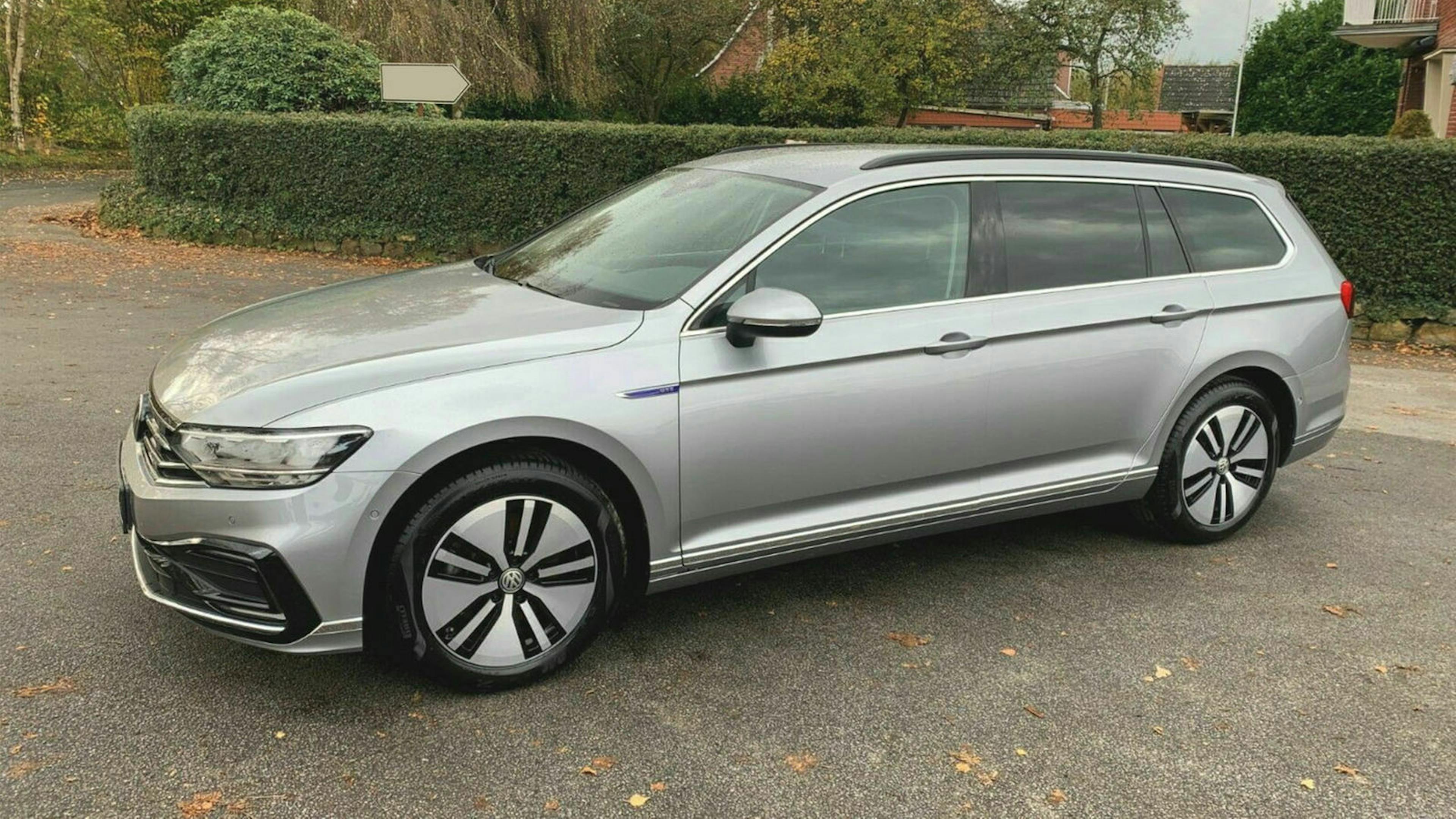 Ein silberner VW Passat steht vor einem Grundstück mit Hecke